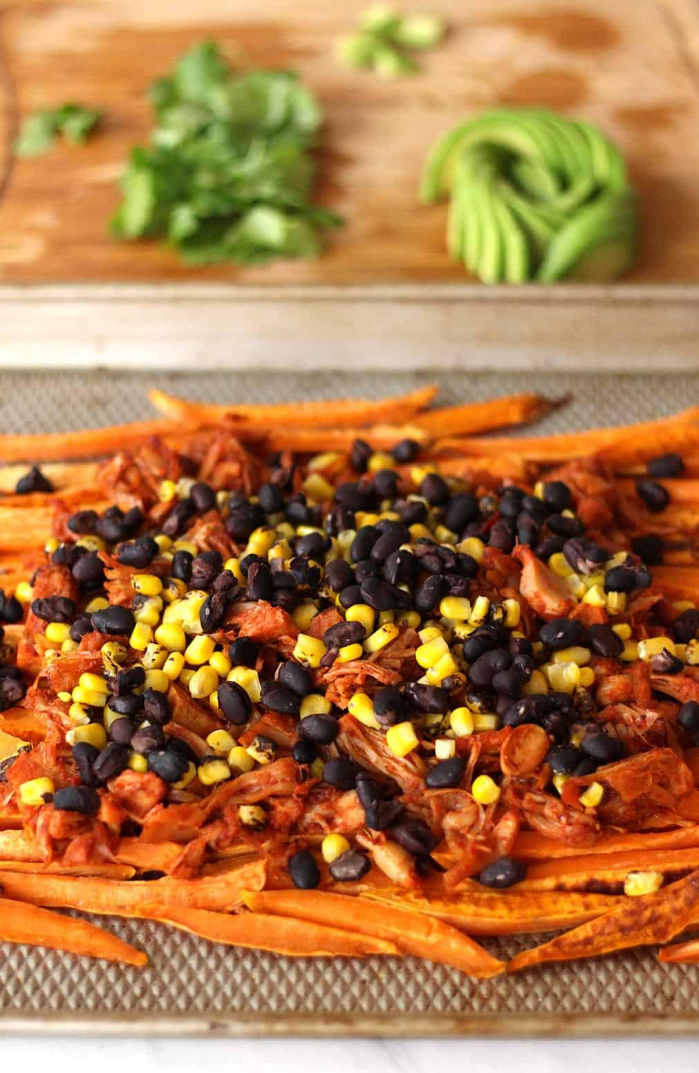 These loaded vegan sweet potato nachos are topped with pulled BBQ jackfruit, a realistic plant based vegetarian alternative to chicken! Topped with a vegan cashew nacho cheese and all the toppings, this recipe is also gluten-free.