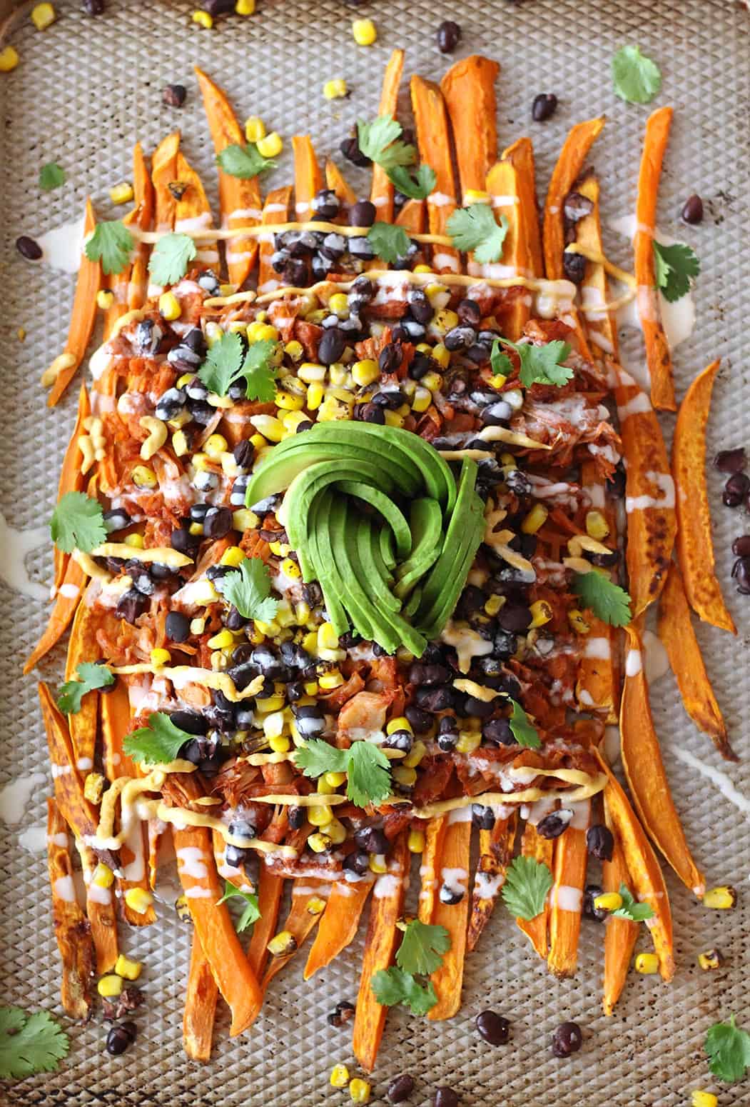 These loaded vegan sweet potato nachos are topped with pulled BBQ jackfruit, a realistic plant based vegetarian alternative to chicken! Topped with a vegan cashew nacho cheese and all the toppings, this recipe is also gluten-free.