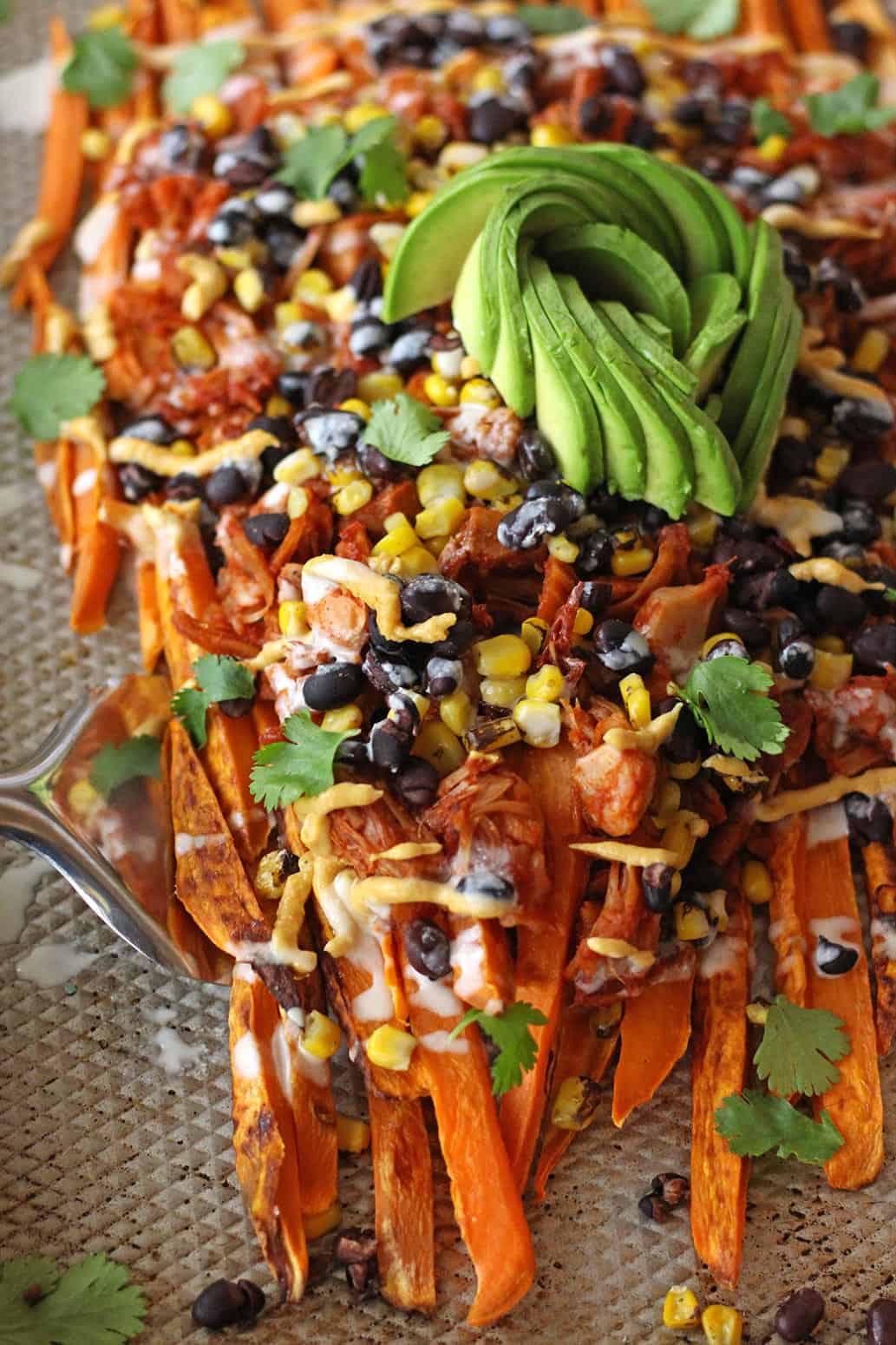 These loaded vegan sweet potato nachos are topped with pulled BBQ jackfruit, a realistic plant based vegetarian alternative to chicken! Topped with a vegan cashew nacho cheese and all the toppings, this recipe is also gluten-free.