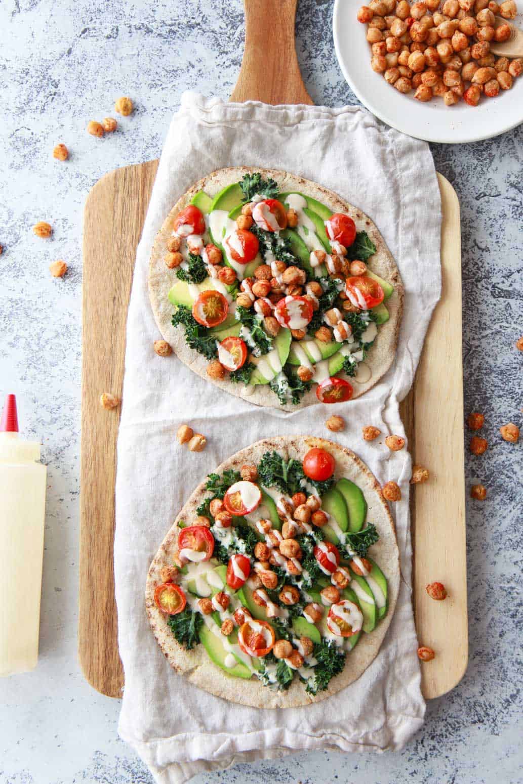 This avocado pita with spiced chickpeas and tahini puts a Mediterranean twist on avocado toast. This vegan recipe is topped with burst cherry tomatoes and massaged kale.