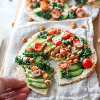 This avocado pita with spiced chickpeas and tahini puts a Mediterranean twist on avocado toast. This vegan recipe is topped with burst cherry tomatoes and massaged kale.