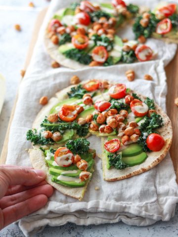 This avocado pita with spiced chickpeas and tahini puts a Mediterranean twist on avocado toast. This vegan recipe is topped with burst cherry tomatoes and massaged kale.