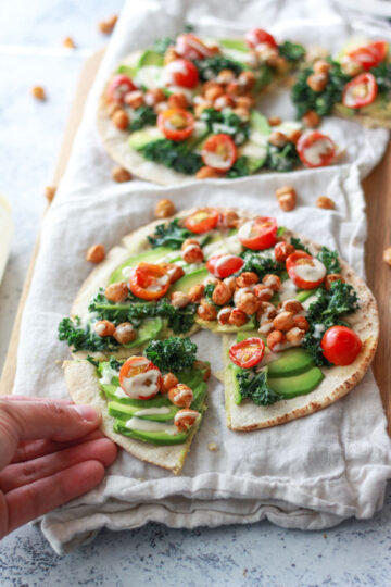 This avocado pita with spiced chickpeas and tahini puts a Mediterranean twist on avocado toast. This vegan recipe is topped with burst cherry tomatoes and massaged kale.