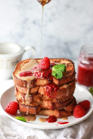 This vegan French toast is made with coconut milk, topped with a raspberry chia jam and coconut creme anglaise. This vegan raspberries and cream French toast has an eggy flavor and stays crispy due to chickpea flour.