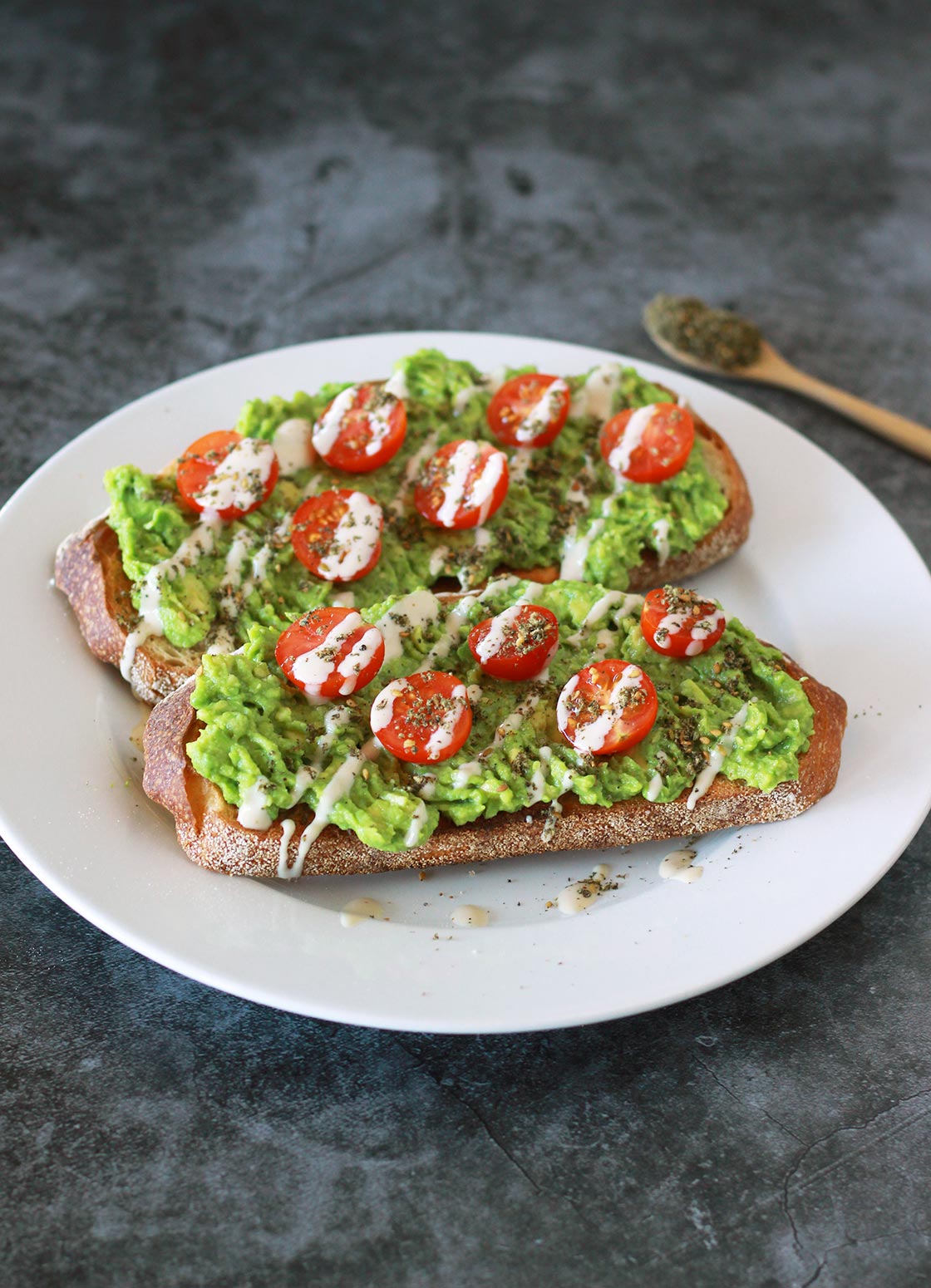 This zaatar avocado toast is a Mediterranean twist on your classic avocado toast, dressed with juicy cherry tomatoes and a creamy 3-ingredient tahini drizzle. This vegan recipe is a modern twist on the classic Middle Eastern breakfast staple of bread with zaatar and olive oil.