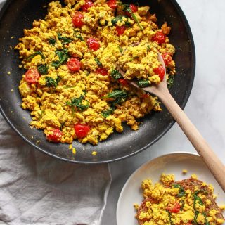 How to make a super flavorful tofu scramble with spinach and cherry tomatoes. Forget about “bland” tofu, this tofu scramble is bursting with umami flavor, seasoned with nutritional yeast and tahini. A great plant-based alternative to scrambled eggs, this flavorful tofu scramble recipe is sure to be a vegan breakfast favorite!