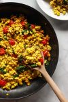 How to make a super flavorful tofu scramble with spinach and cherry tomatoes. Forget about “bland” tofu, this tofu scramble is bursting with umami flavor, seasoned with nutritional yeast and tahini. A great plant-based alternative to scrambled eggs, this flavorful tofu scramble recipe is sure to be a vegan breakfast favorite!
