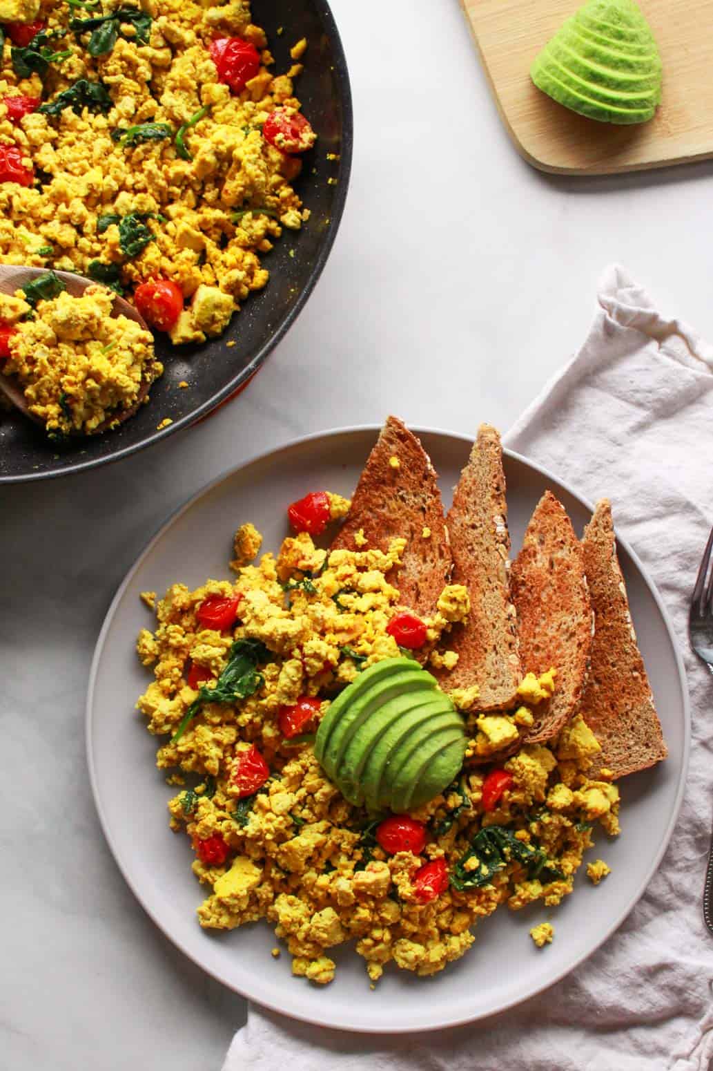 How to make a super flavorful tofu scramble with spinach and cherry tomatoes. Forget about “bland” tofu, this tofu scramble is bursting with umami flavor, seasoned with nutritional yeast and tahini. A great plant-based alternative to scrambled eggs, this flavorful tofu scramble recipe is sure to be a vegan breakfast favorite!