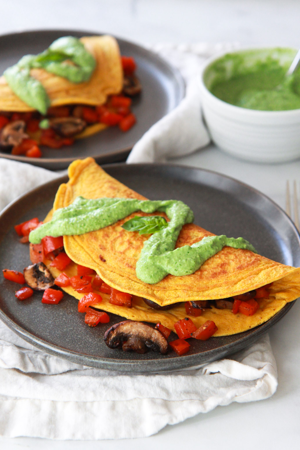 This chickpea omelet recipe is a delicious vegan alternative to a traditional egg omelet. Also gluten-free, this chickpea omelet does not crack or break when flipped, can be stuffed with your favorite veggies, and is topped with a dairy-free avocado pesto.