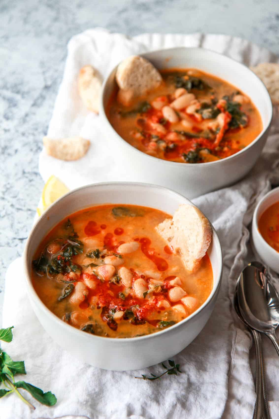 This Mediterranean white bean soup is flavored with Harissa and tahini. Filled with kale, parsley, and thyme, this vegan white bean soup is hearty, flavorful, and creamy.