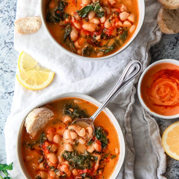 This Mediterranean white bean soup is flavored with Harissa and tahini. Filled with kale, parsley, and thyme, this vegan white bean soup is hearty, flavorful, and creamy.