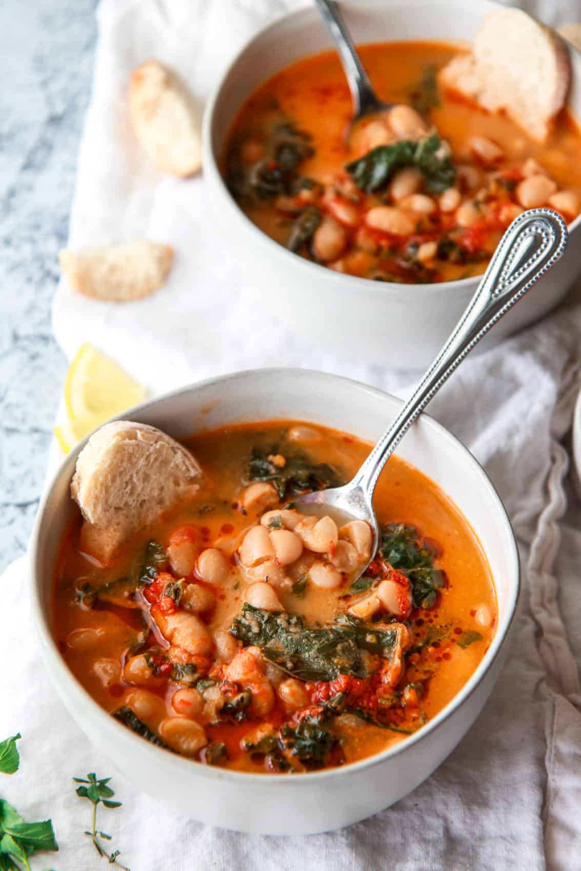 This Mediterranean white bean soup is flavored with Harissa and tahini. Filled with kale, parsley, and thyme, this vegan white bean soup is hearty, flavorful, and creamy.