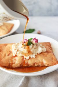 This vegan Kahi with Geymar is an Iraqi pastry with a thick oat cream, topped with date syrup. This pastry is made up of layers of flaky phyllo dough, topped with vegan clotted cream, called Qaymar. Topped with date syrup or honey for a non-vegan option, this dessert is irresistible.