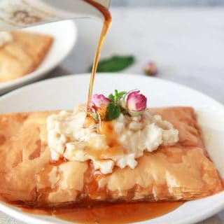 This vegan Kahi with Geymar is an Iraqi pastry with a thick oat cream, topped with date syrup. This pastry is made up of layers of flaky phyllo dough, topped with vegan clotted cream, called Qaymar. Topped with date syrup or honey for a non-vegan option, this dessert is irresistible.