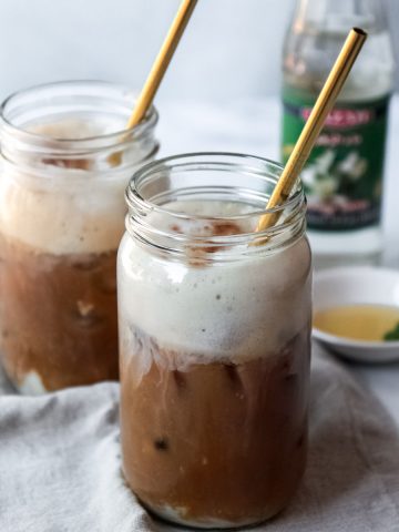 Foamy Iced Oat Milk Latte with Orange Blossom Water, Vegan, topped with cinnamon.