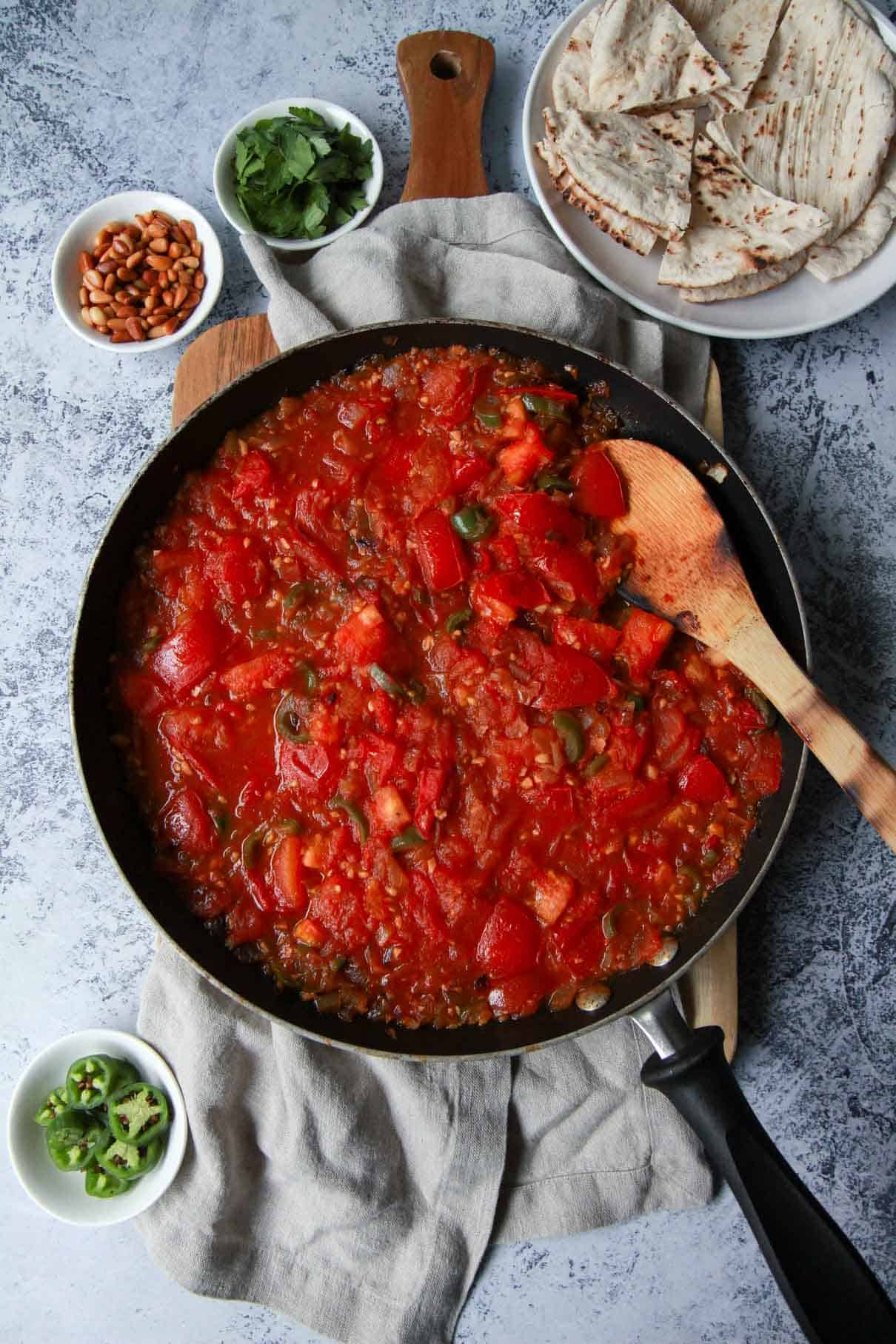 This image shows the process of sautéing tomatoes for galayet bandora.