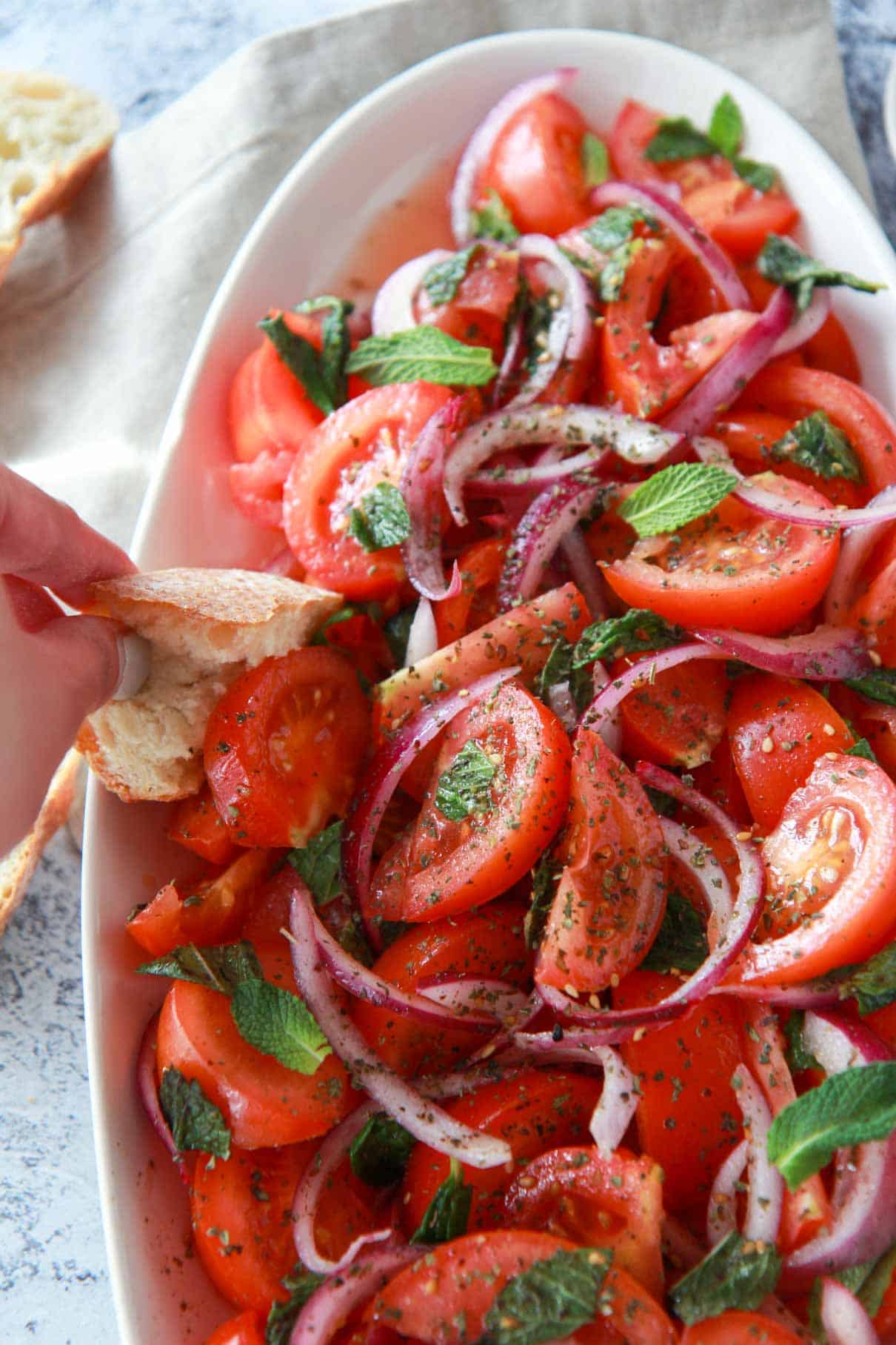 how to serve tomato and red onion salad, featuring scooping up the tomato salad with bread