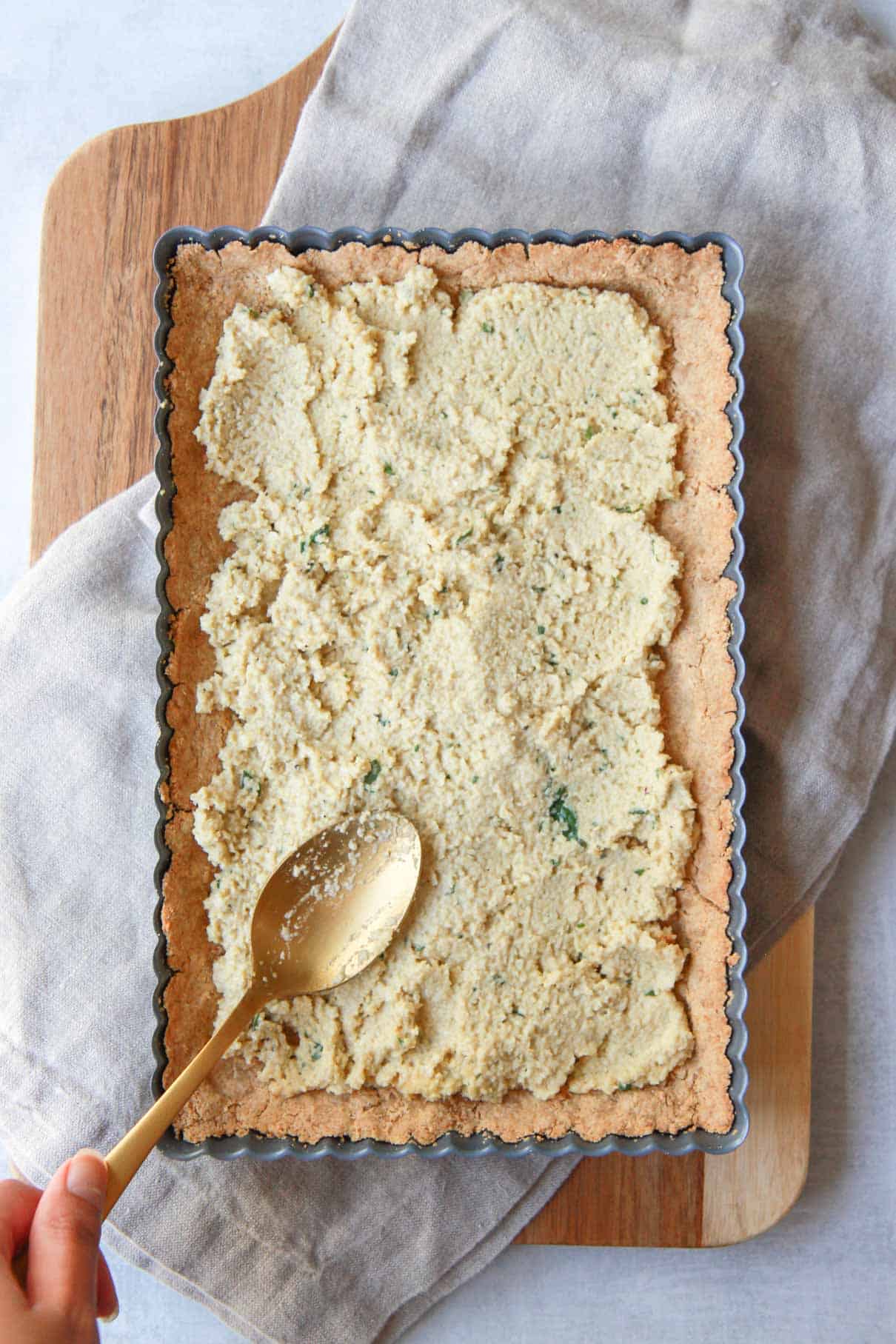 Spreading the basil cashew ricotta over the vegan gluten free tart crust