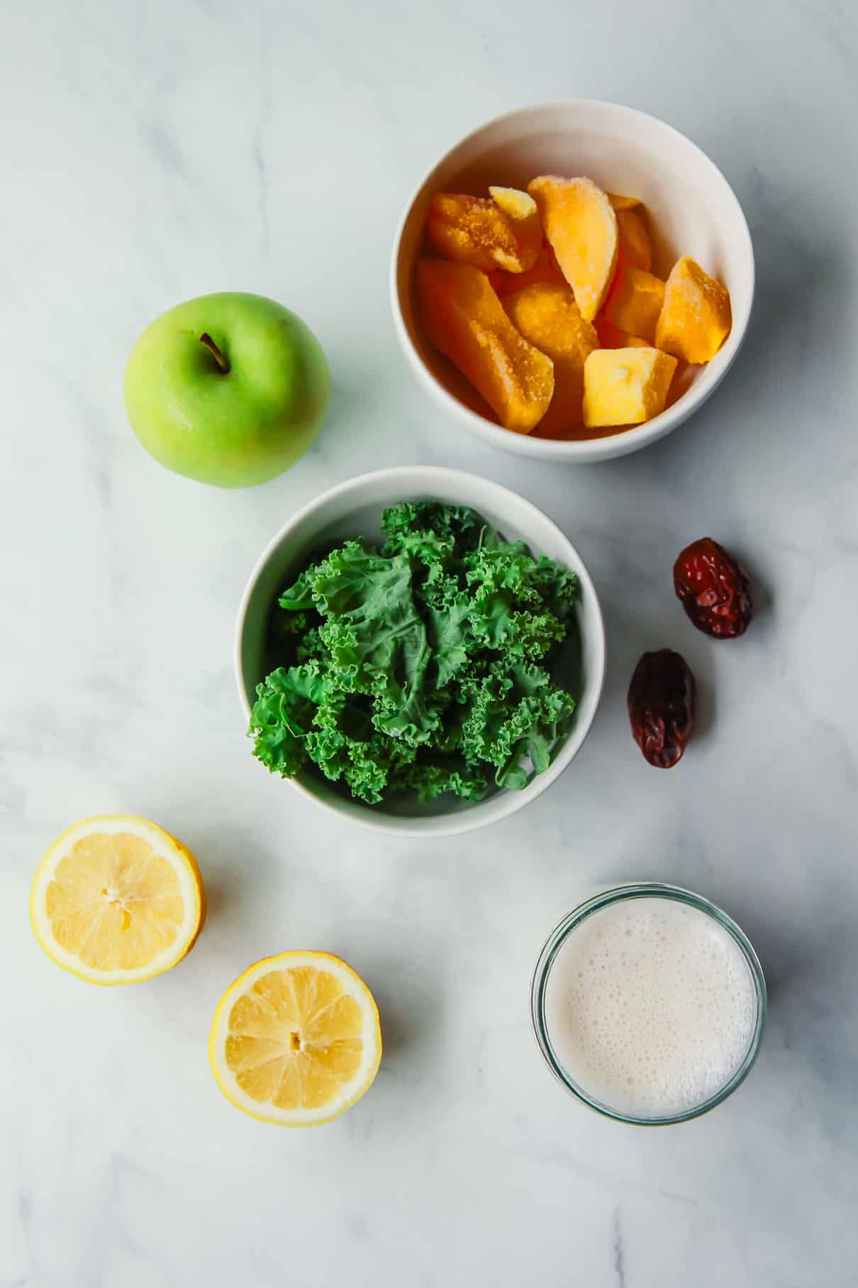 The kale apple smoothie ingredients which include lemon, almond milk, dates, kale, frozen mango, and green apple