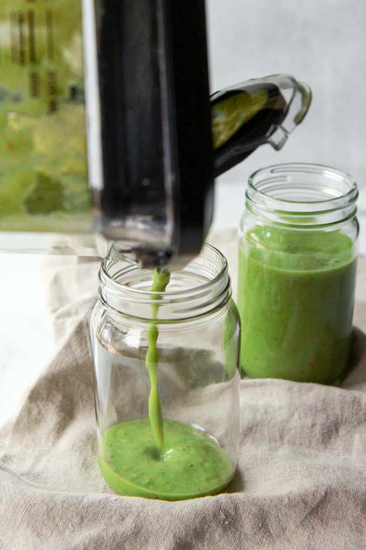 Blender pouring the kale apple smoothie into a jar