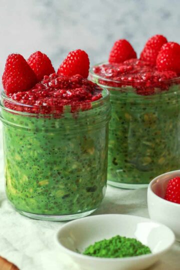 Image featuring a straight on shot of the overnight matcha oats topped with raspberry chia jam cropped square