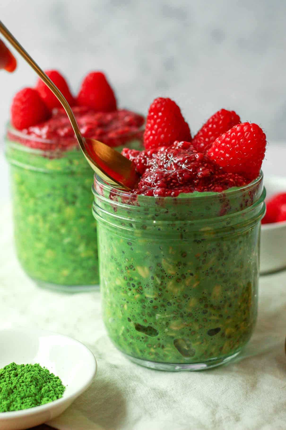 Spoon scooping the overnight matcha oats with raspberry chia jam