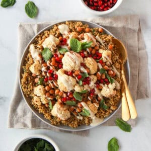 The freekeh recipe shown with the cooked freekeh, topped with roasted cauliflower and chickpeas and drizzled with tahini.