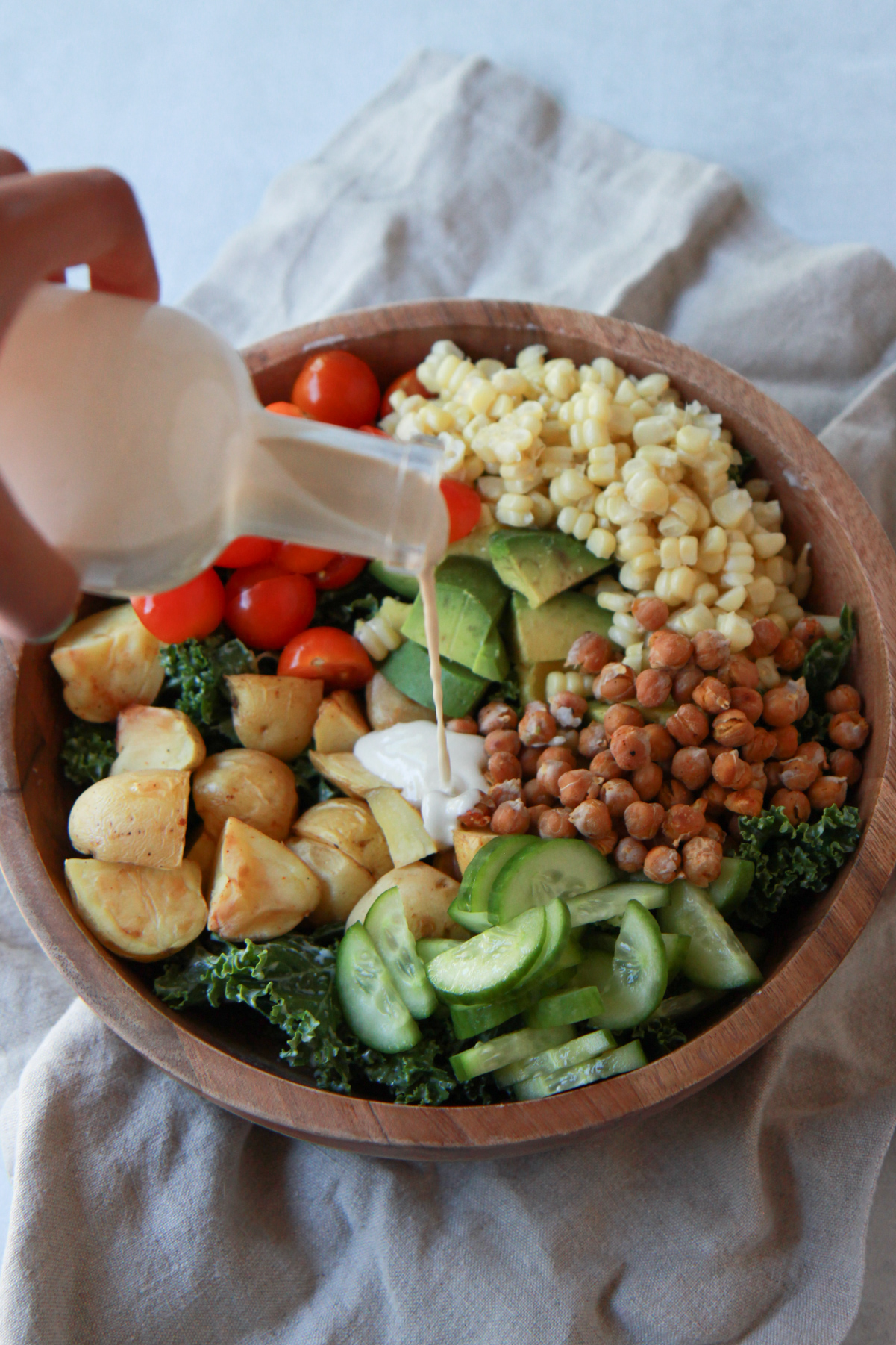 Tahini sauce being drizzled over a kale salad.