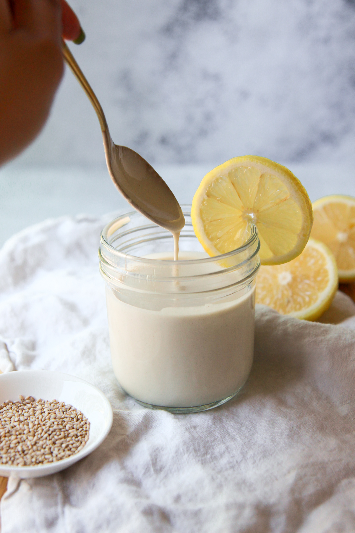 The tahini sauce being drizzled with a spoon to show consistency.