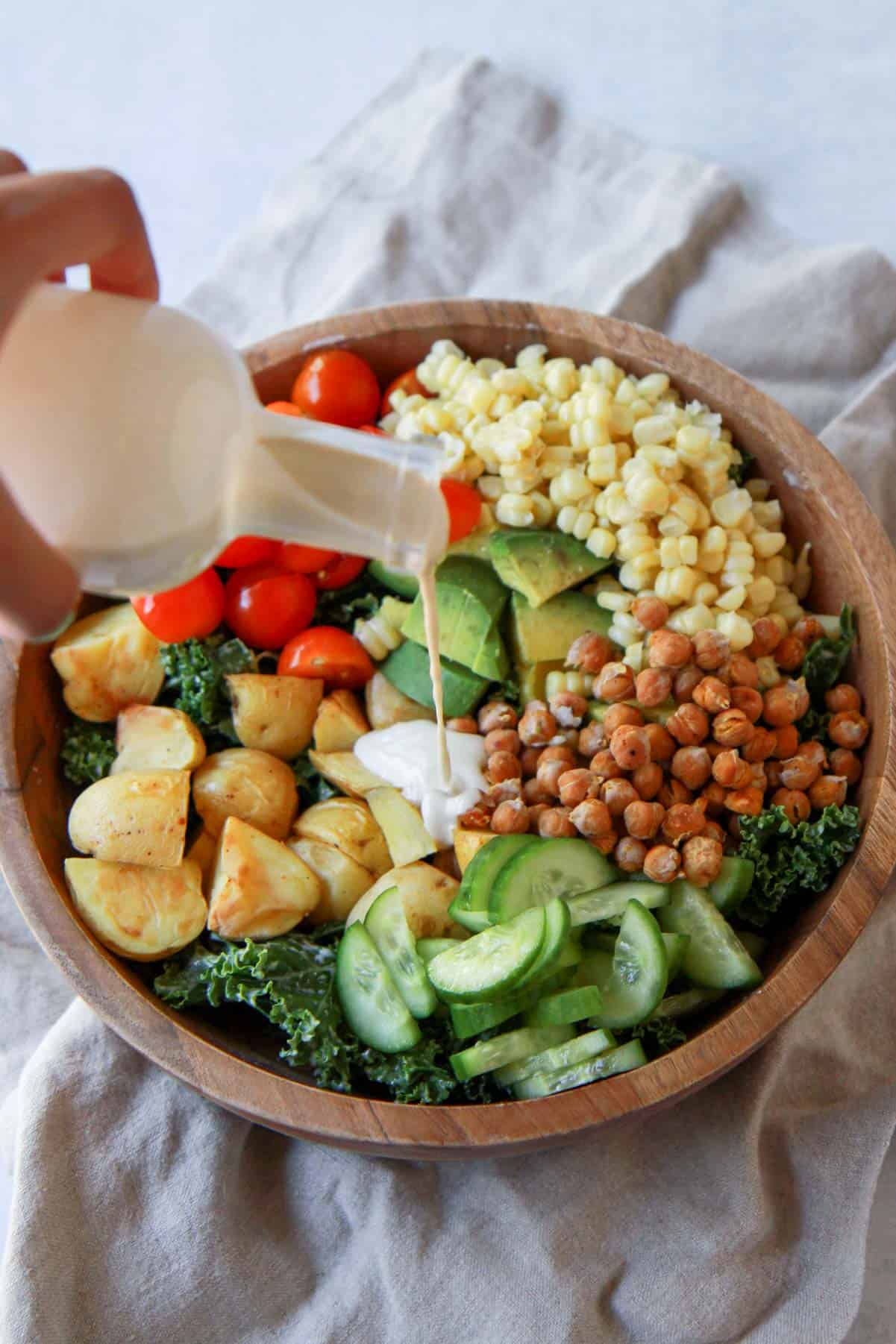 Pouring the tahini dressing over the kale salad.