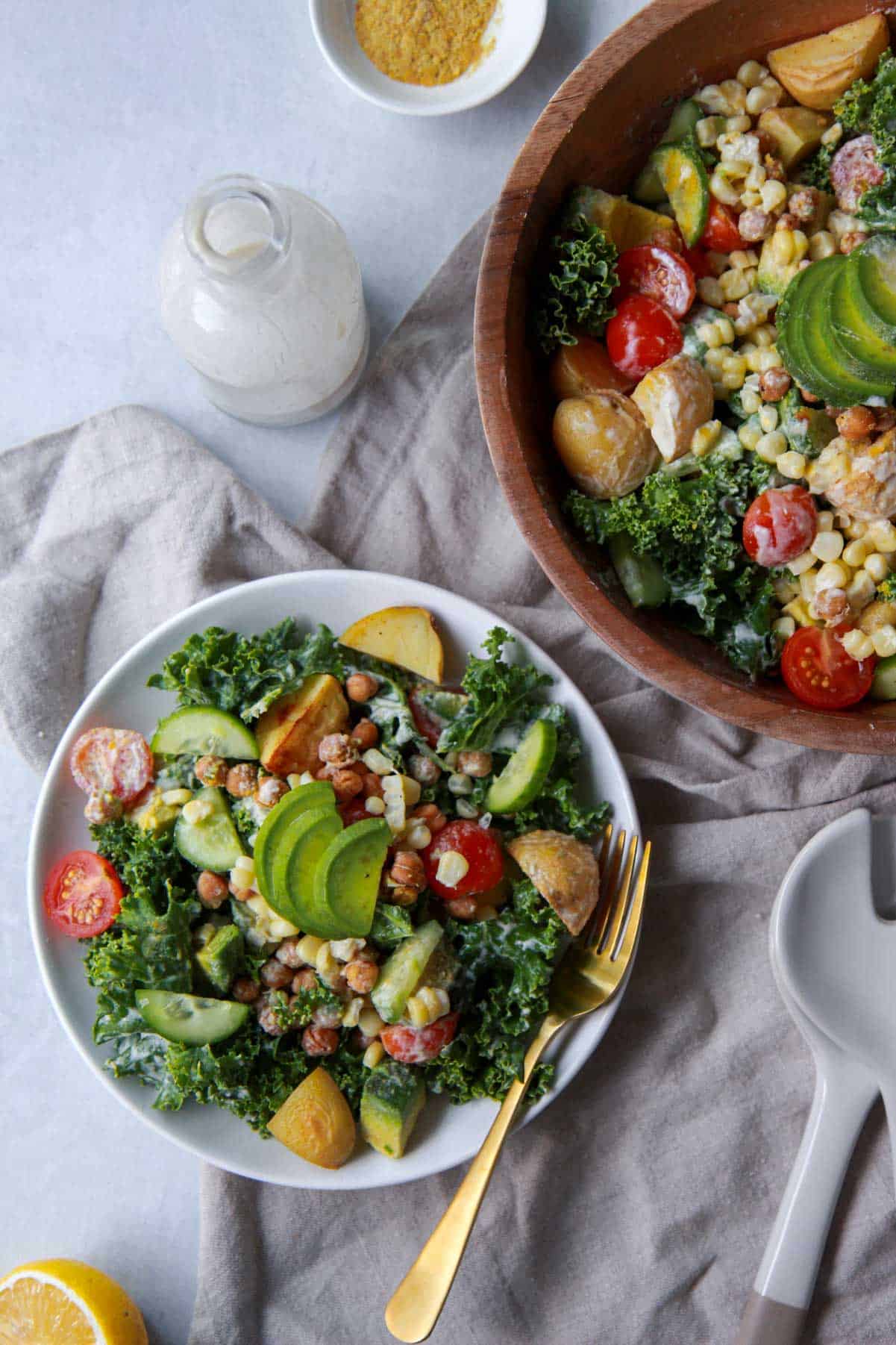 An image of the kale salad, dressed in tahini dressing, being served on a plate with more dressing on the side.