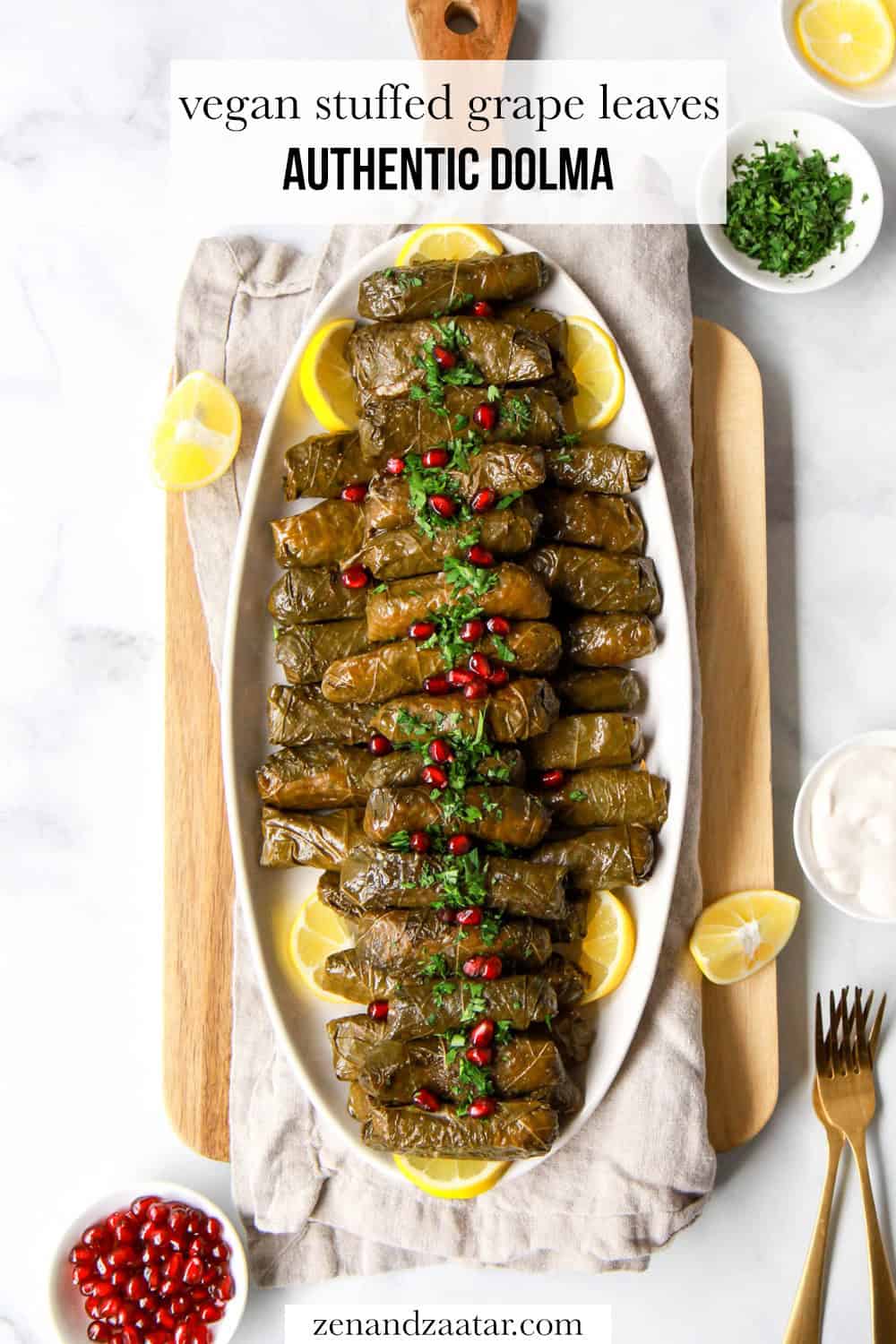 This yalanji dolma recipe is plated and garnished, with text overlay, "vegan stuffed grape leaves - authentic dolma."