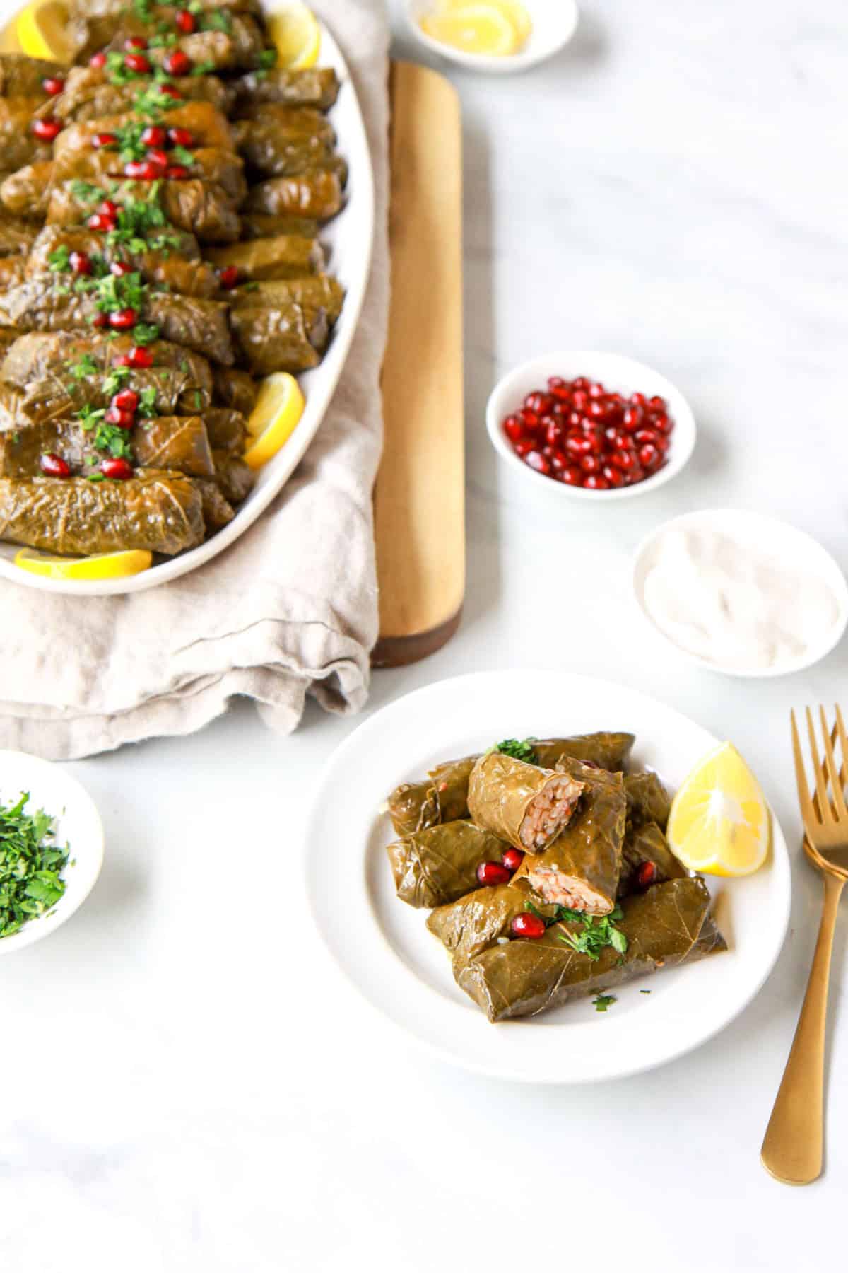 Plated, complete yalanji dolma with a cross section of a yalanji plated as well.