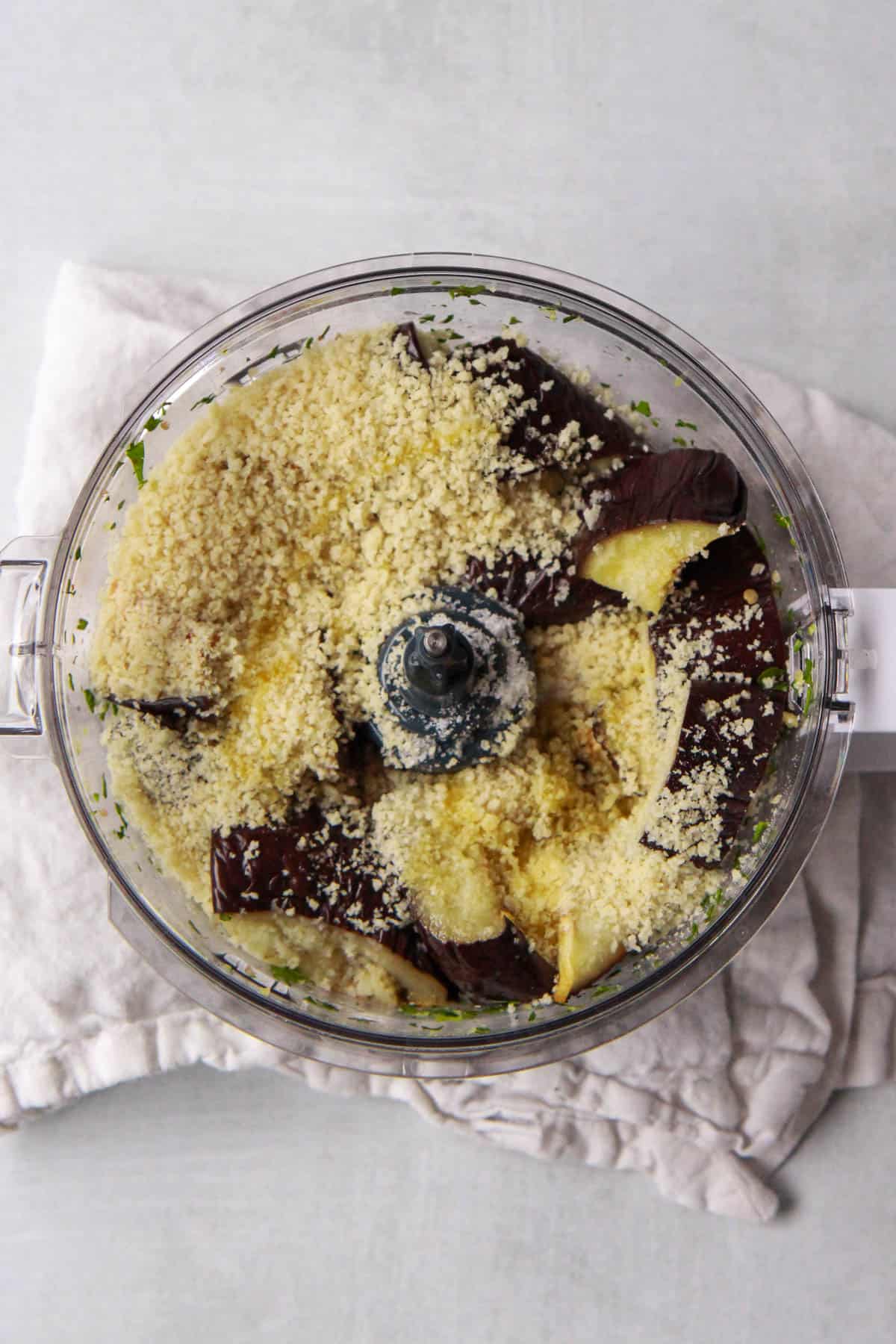 The chopped eggplant and other ingredients being added to the food processor, after pulsing the walnut crumbs.