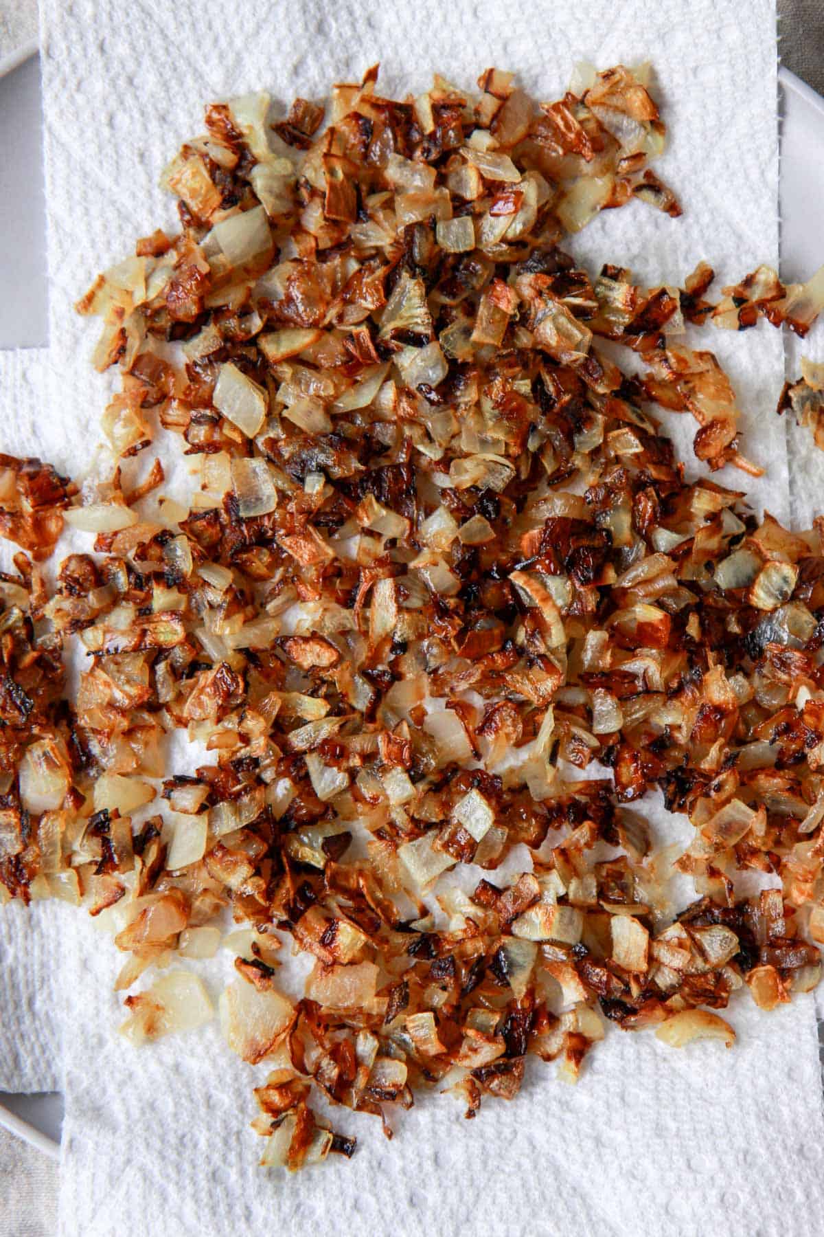 How the onions look after crisping on the stovetop, drying on a paper-towel-lined plate.