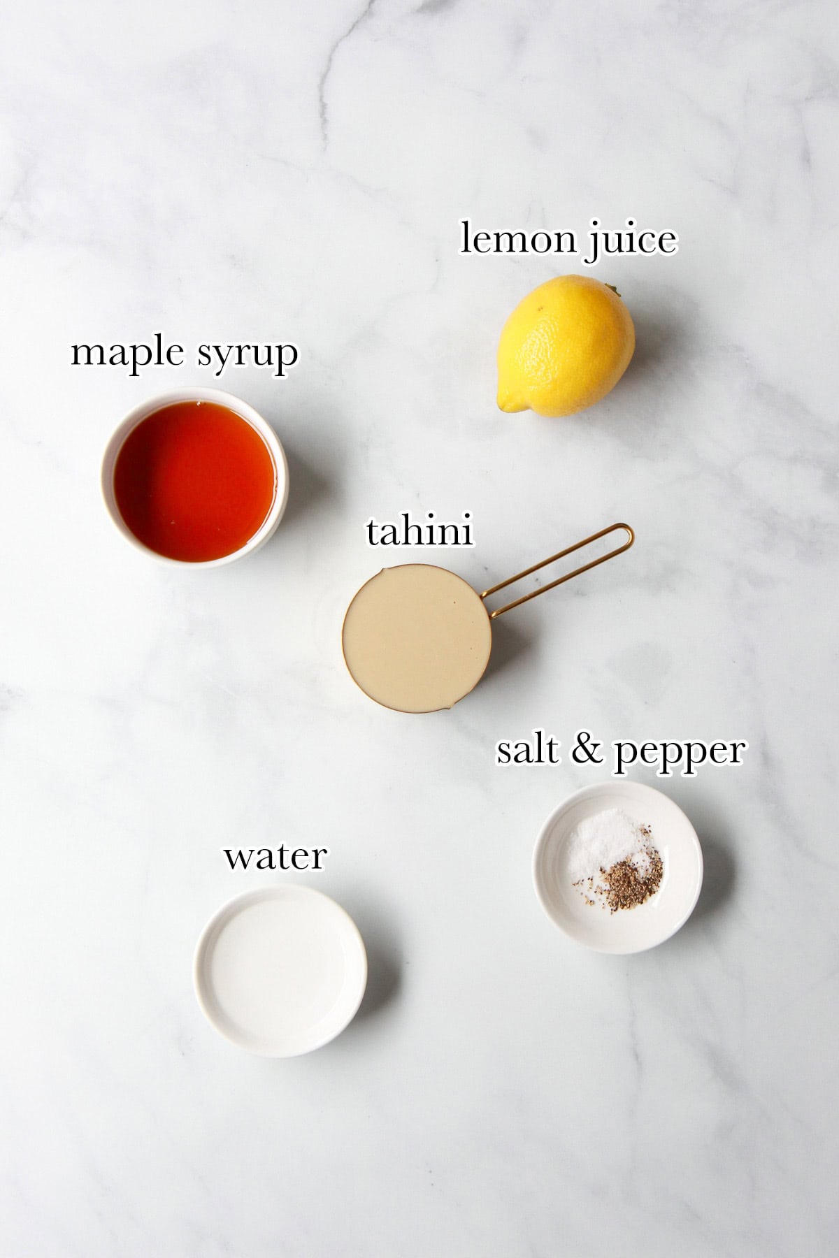 The ingredients you need for maple tahini dressing displayed on a marble countertop.