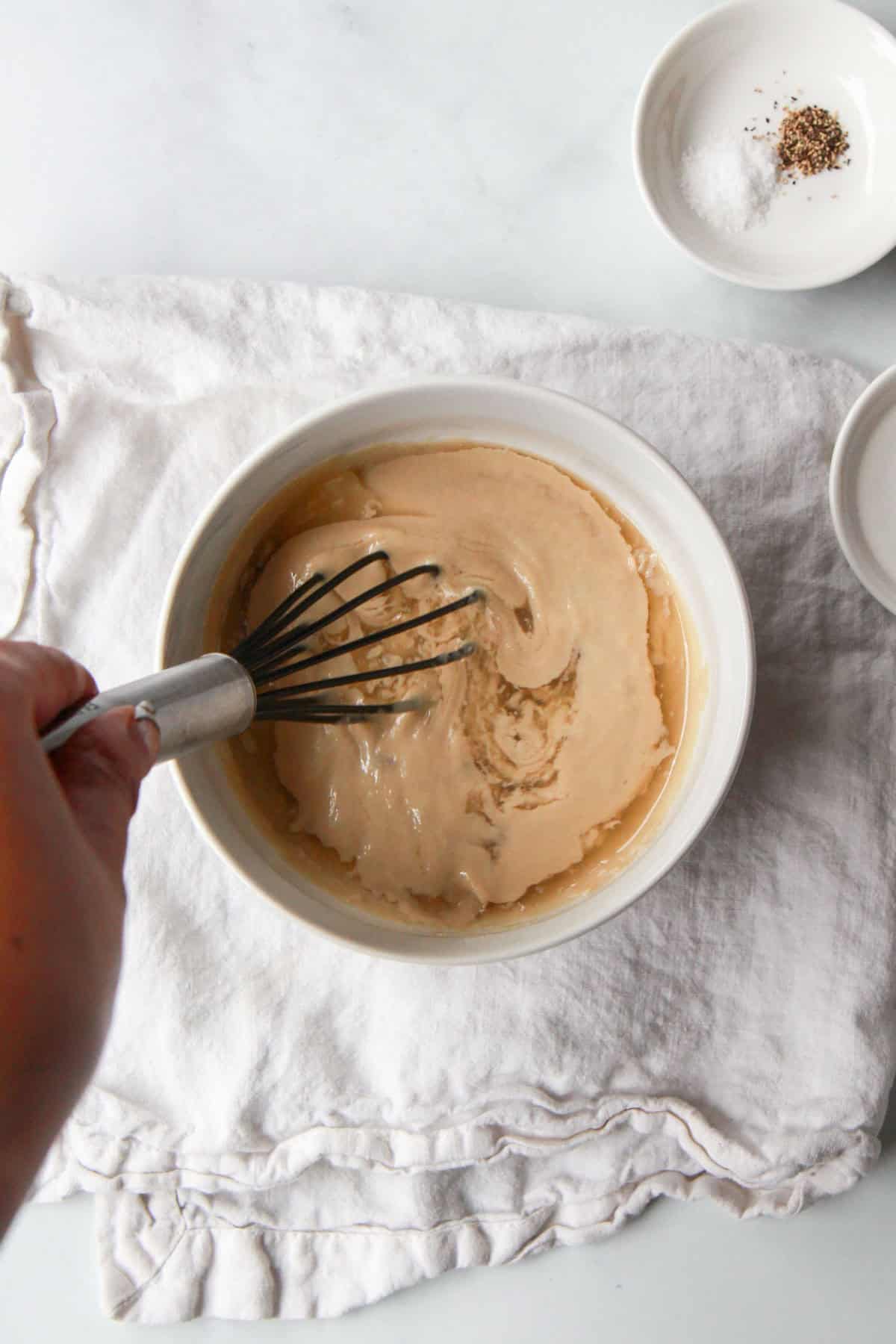 Whisking the tahini, maple, and lemon juice together.