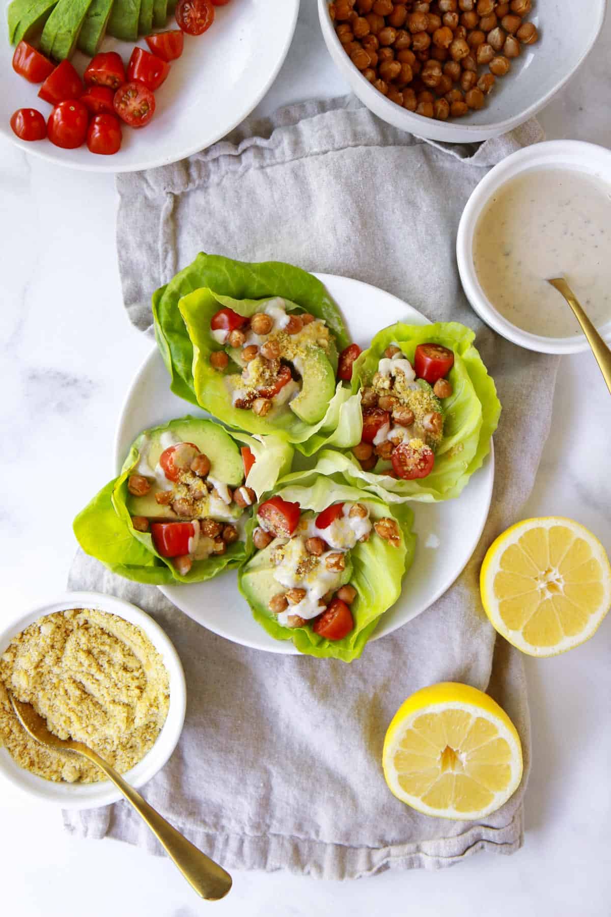 Four vegan Caesar wraps arranged in a flatlay image surrounded by chickpeas, Caesar, and almond Parm.