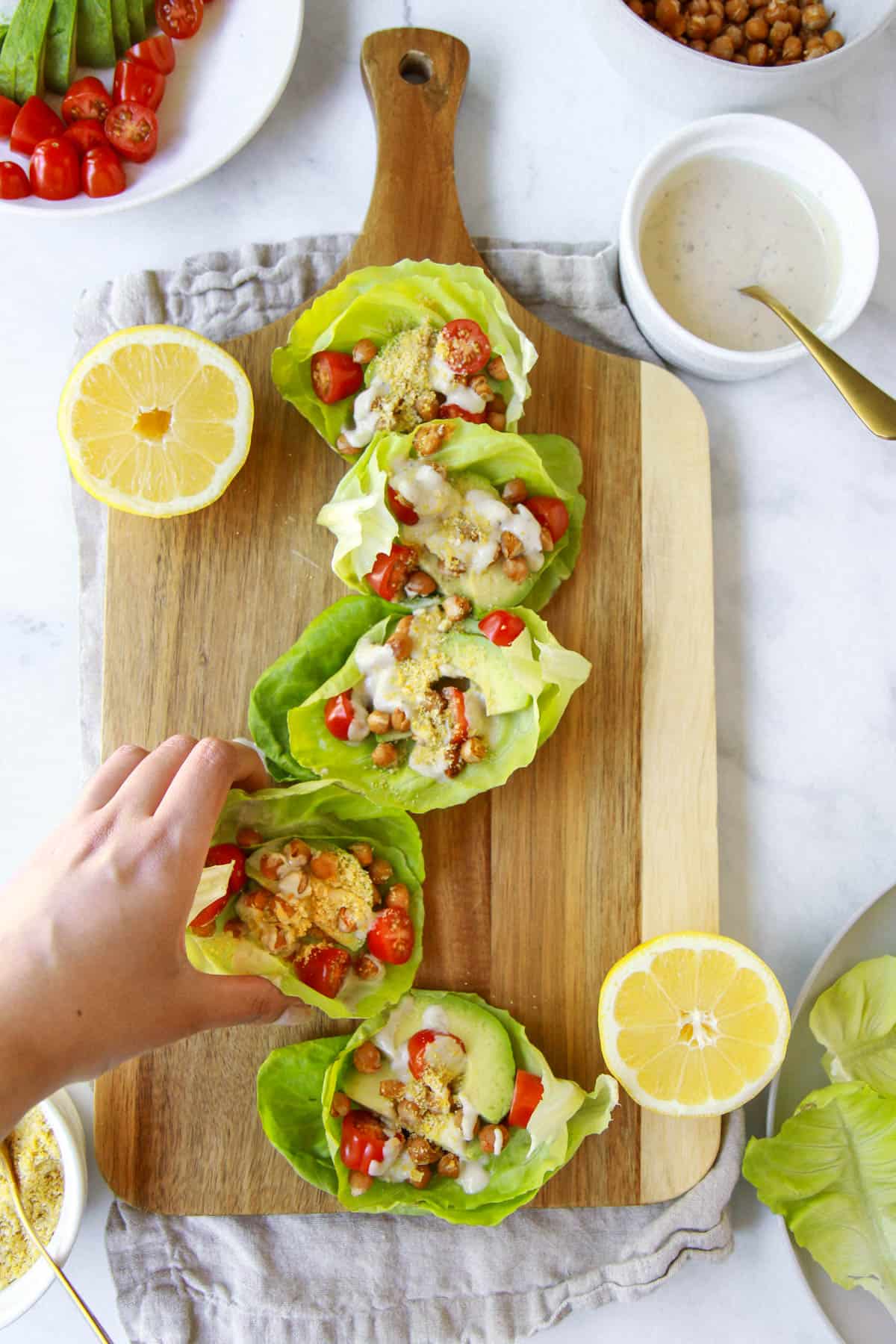 A hand grabbing one of the vegan Caesar wraps.
