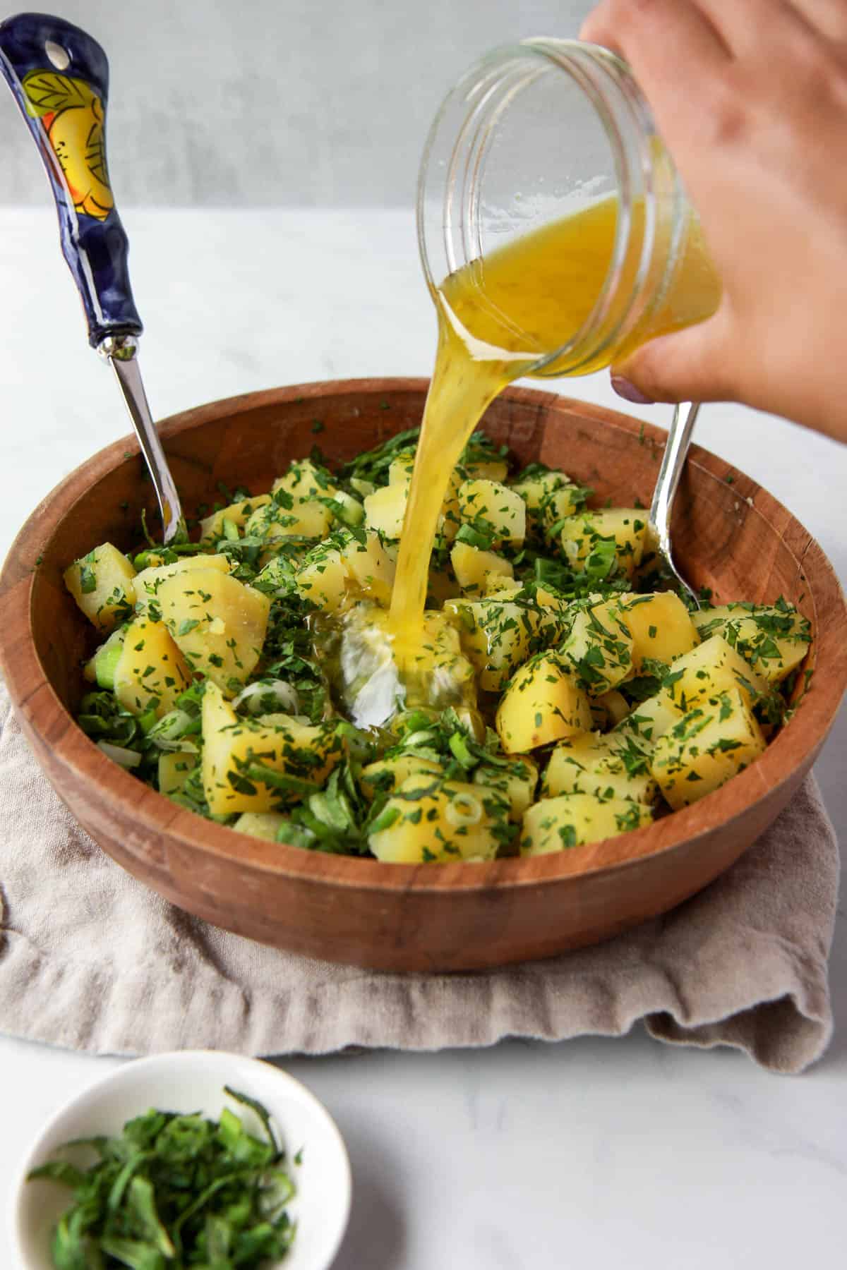 Pouring salad dressing over Arabic potato salad.