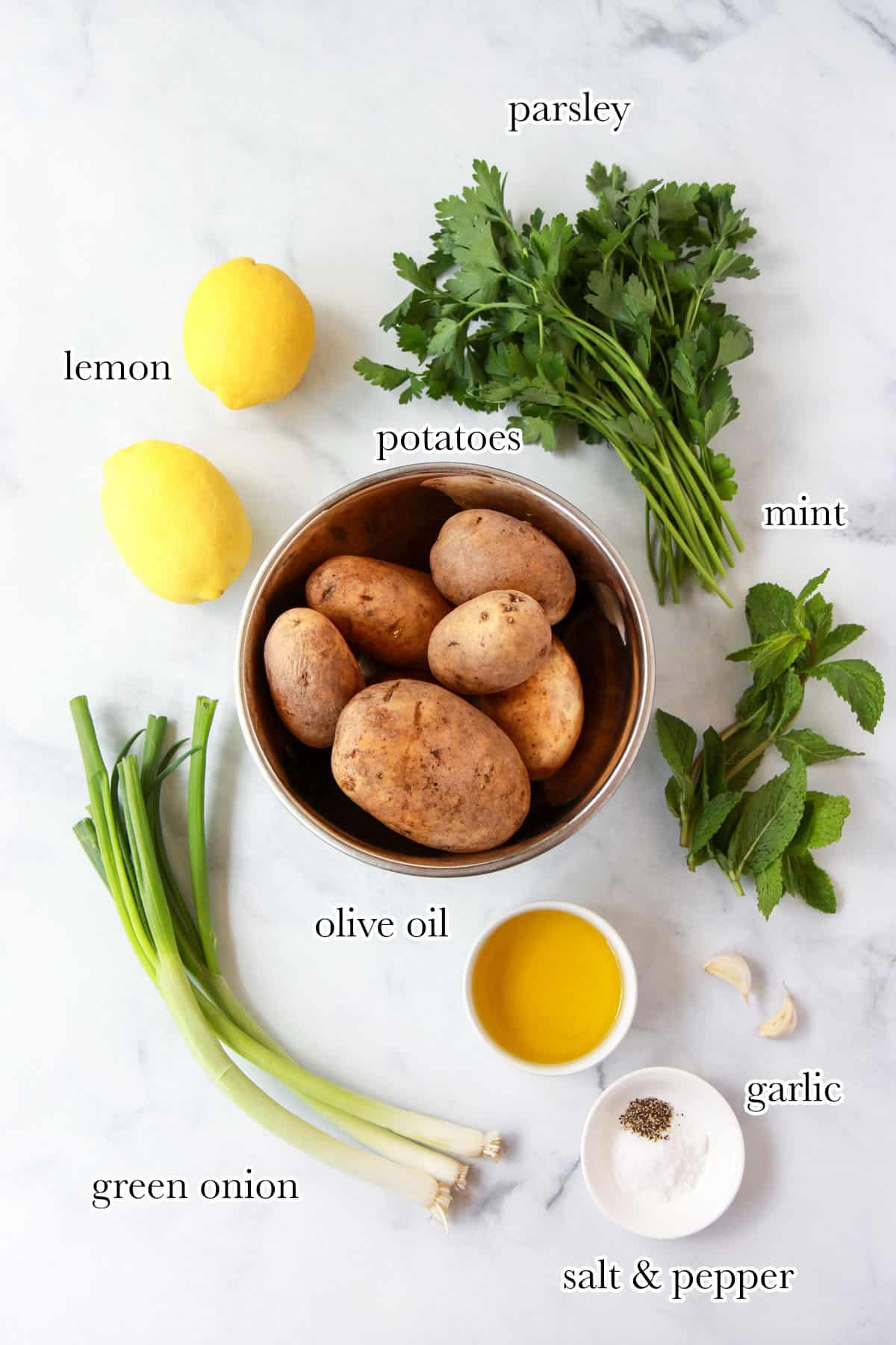 Mediterranean potato salad ingredients including potatoes, green onions, garlic, lemon, parsley, salt, and olive oil.