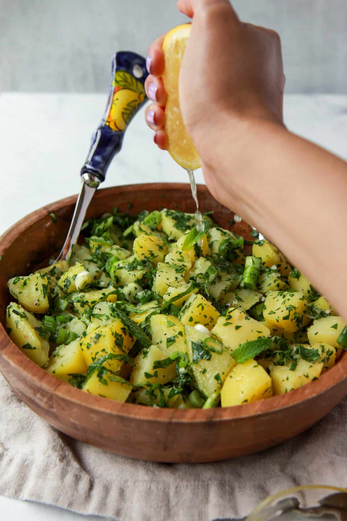 Squeezing lemon juice over Mediterranean potato salad.
