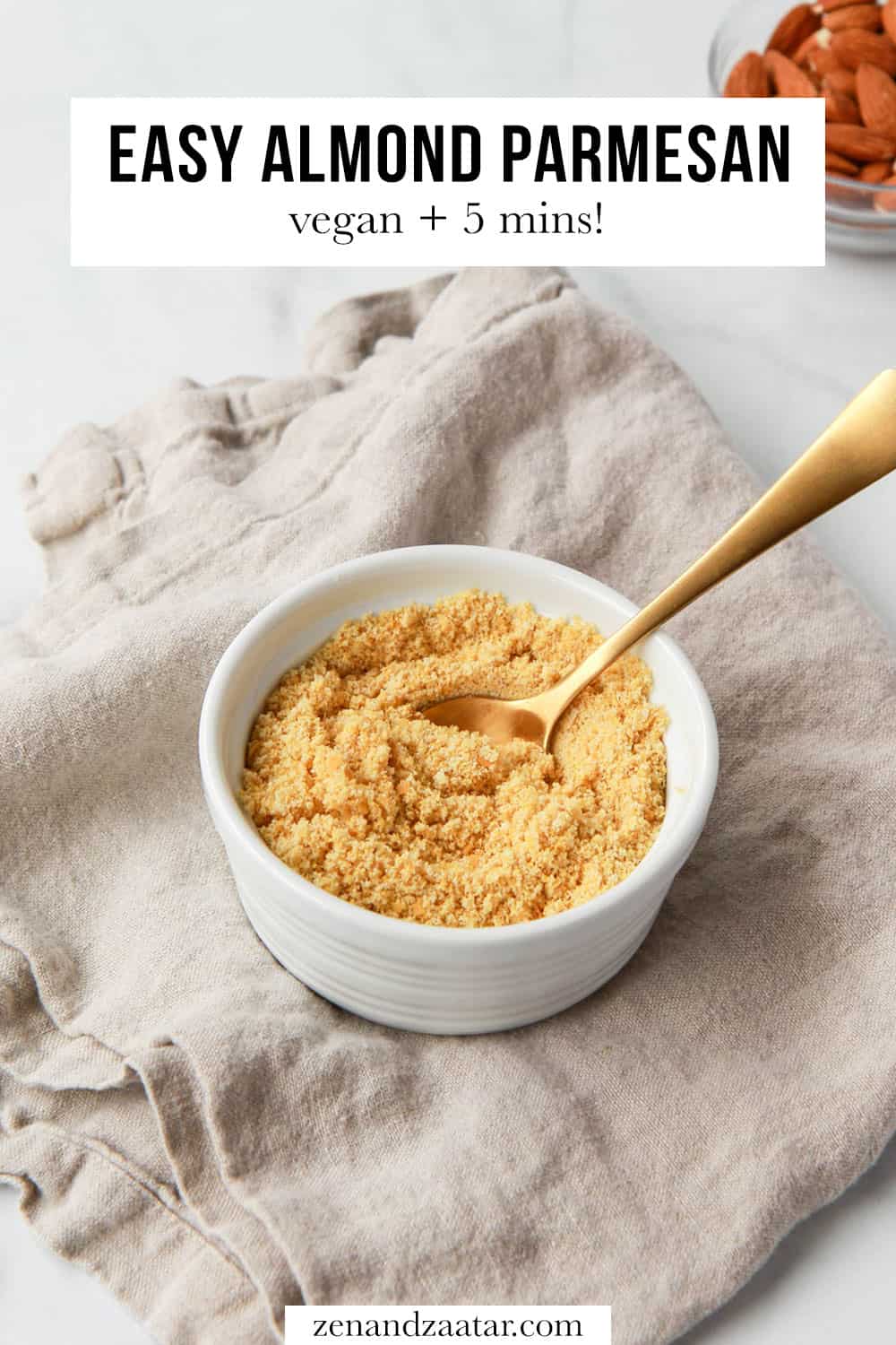 Almond parmesan cheese in a white bowl with a gold spoon, with text overlay, "Easy almond parmesan: vegan + 5 mins."