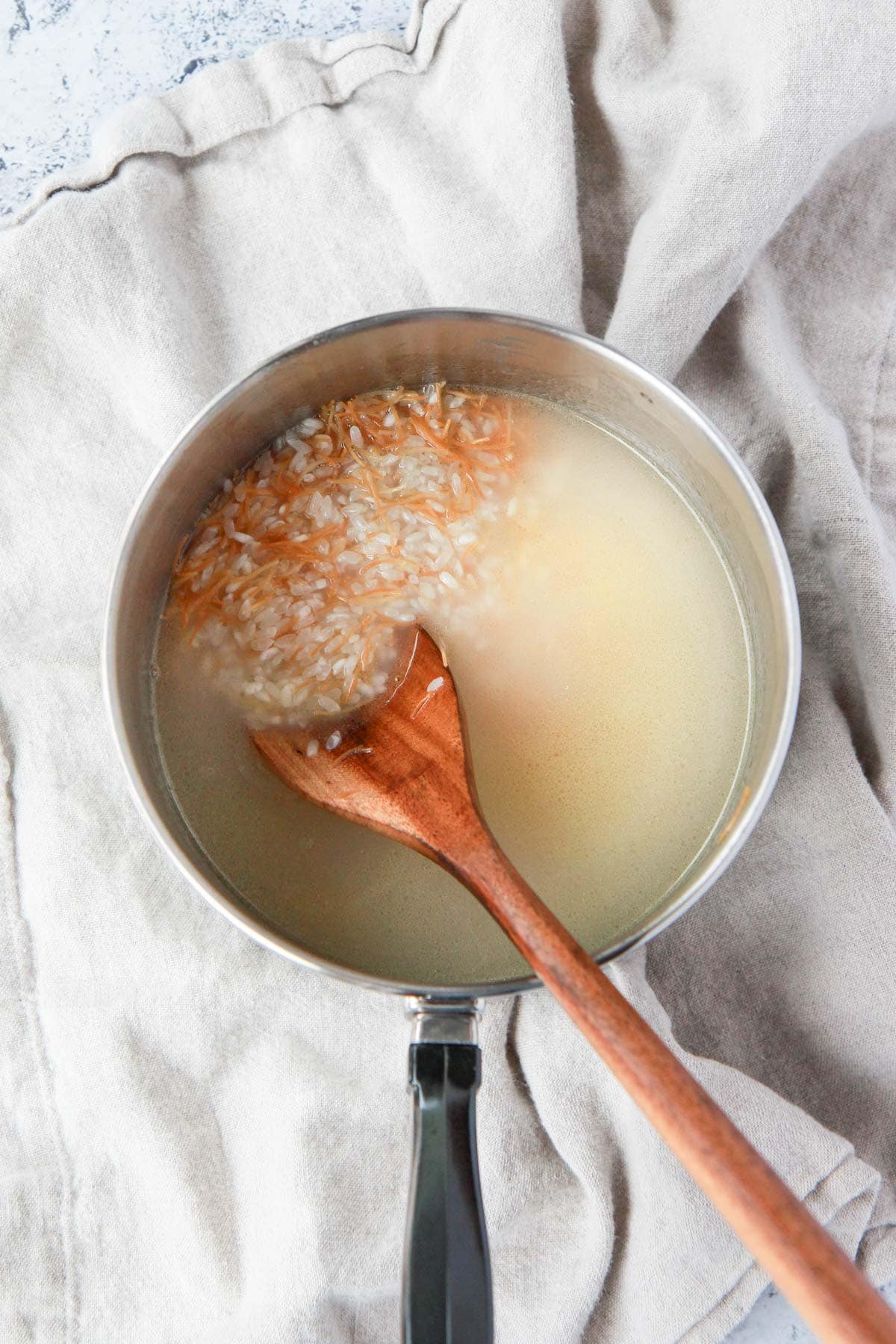 Adding water to toasted rice and vermicelli.