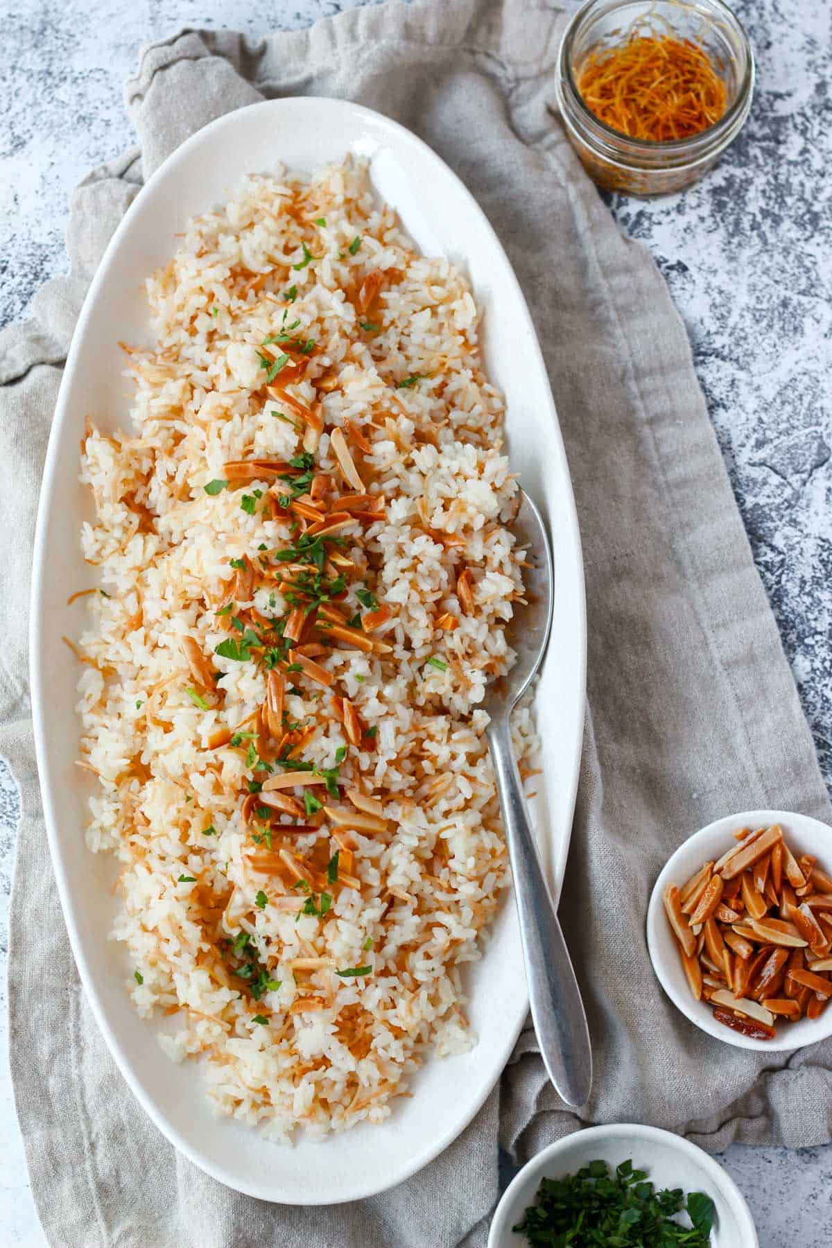 Close-up image of finished vermicelli rice with spoon, topped with toasted almonds and parsley.