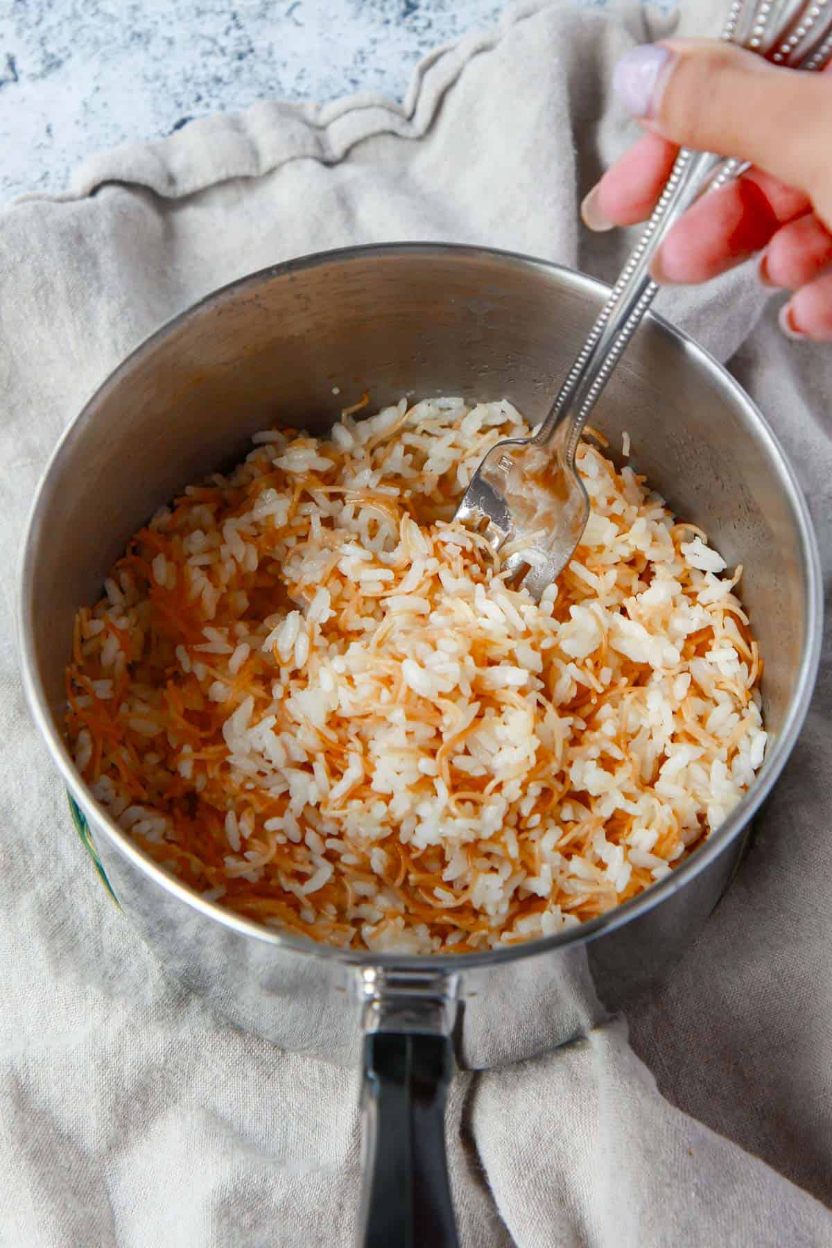 Fluffing vermicelli rice with a fork.