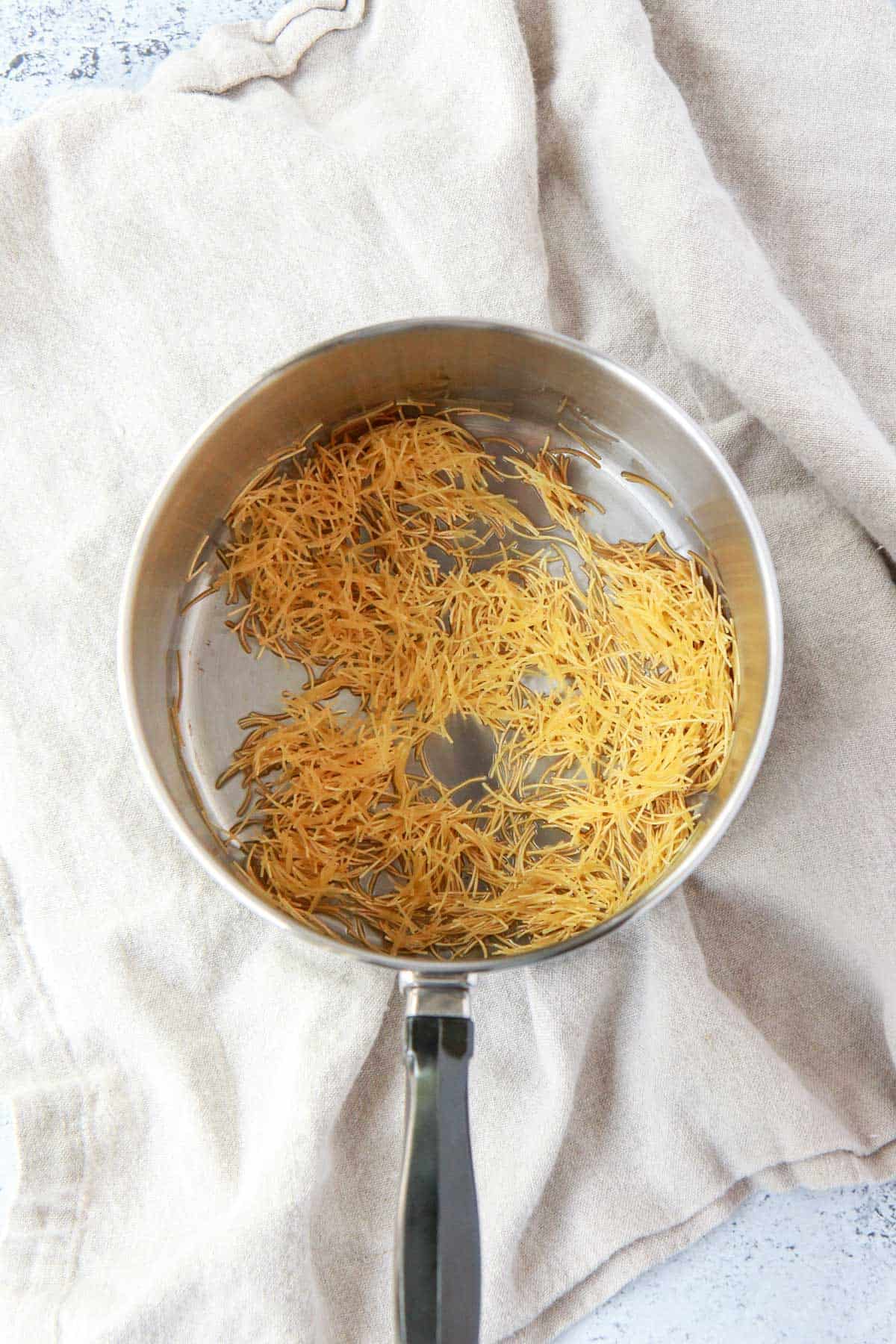 Vermicelli noodles added to pot before toasting.