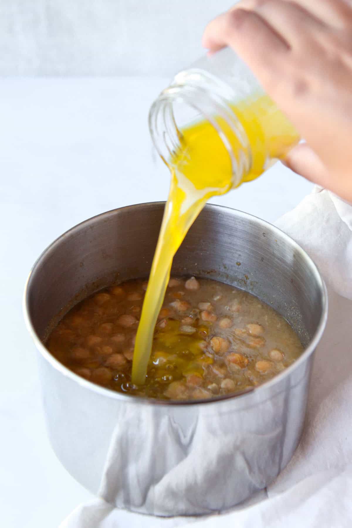 Pouring olive oil and lemon into the pot of balila.