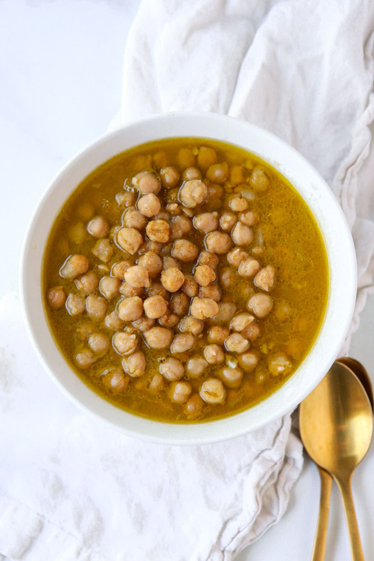 Hummus balila, mixed with cumin, garlic, salt, lemon, and olive oil, warm, in a bowl.