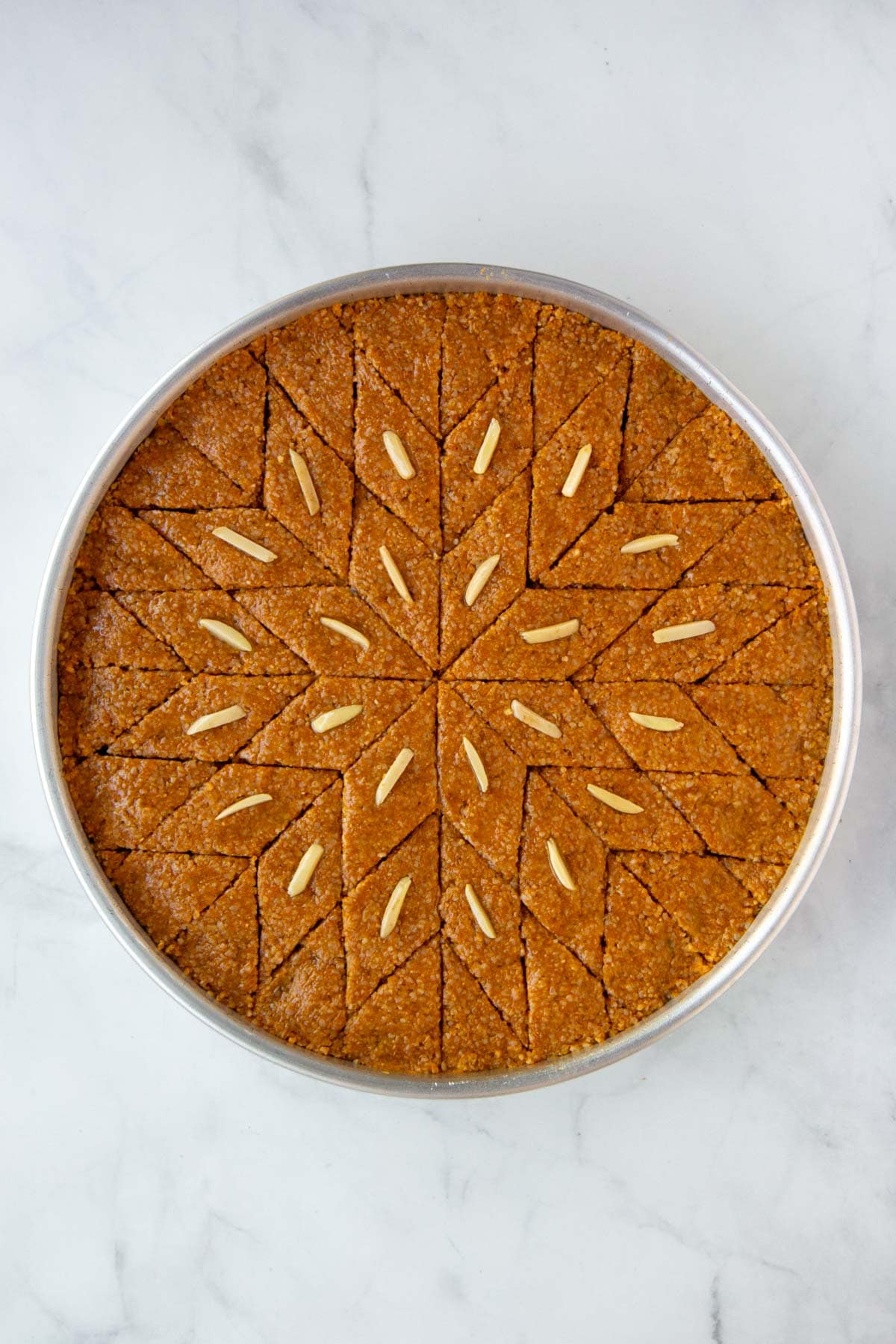 Unbaked kibbeh brushed with olive oil and garnished with nuts.